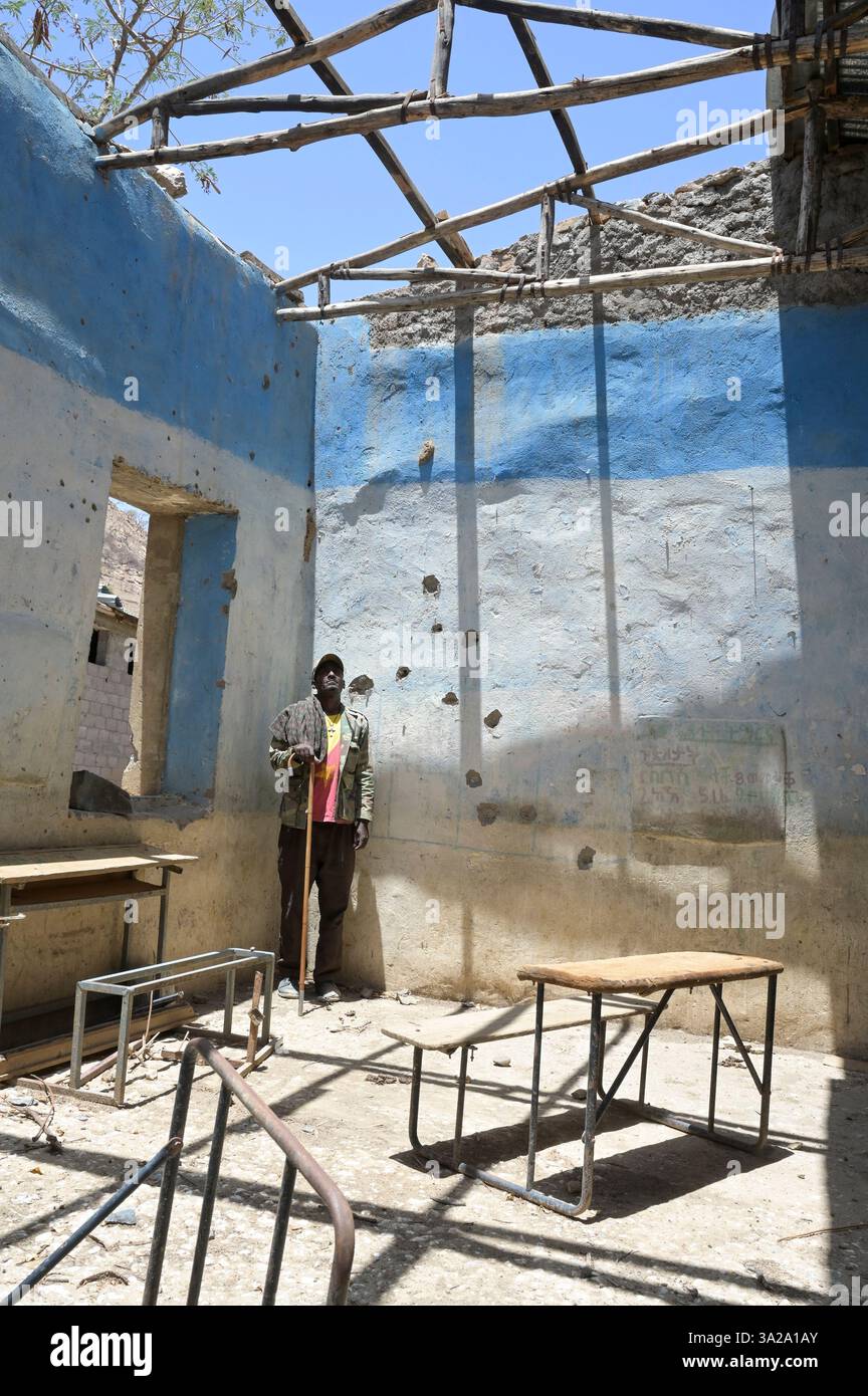 ETIOPIA, Distretto Yechila, villaggio SHEWEATE HUGUM, distrutto scuola durante la guerra Tigra 2020-2022 tra le forze alleate al governo federale etiope e l'Eritrea e il fronte di Liberazione del popolo Tigray TPLF, combattente TPLF / Äthiopien, Tigray, Folgen des Tigray Krieges 2020-2022, Distrikt Yechila, Dorf SHEWEATE HUGUM, zerstörte Schule, Gerse Tadese, Tigrayischer Kämpfer der TPLF, 51 Jahre alt, Sein Sohn ist im Krieg gefallen mit 22 Jahren, Gewehr Einschüsse Foto Stock