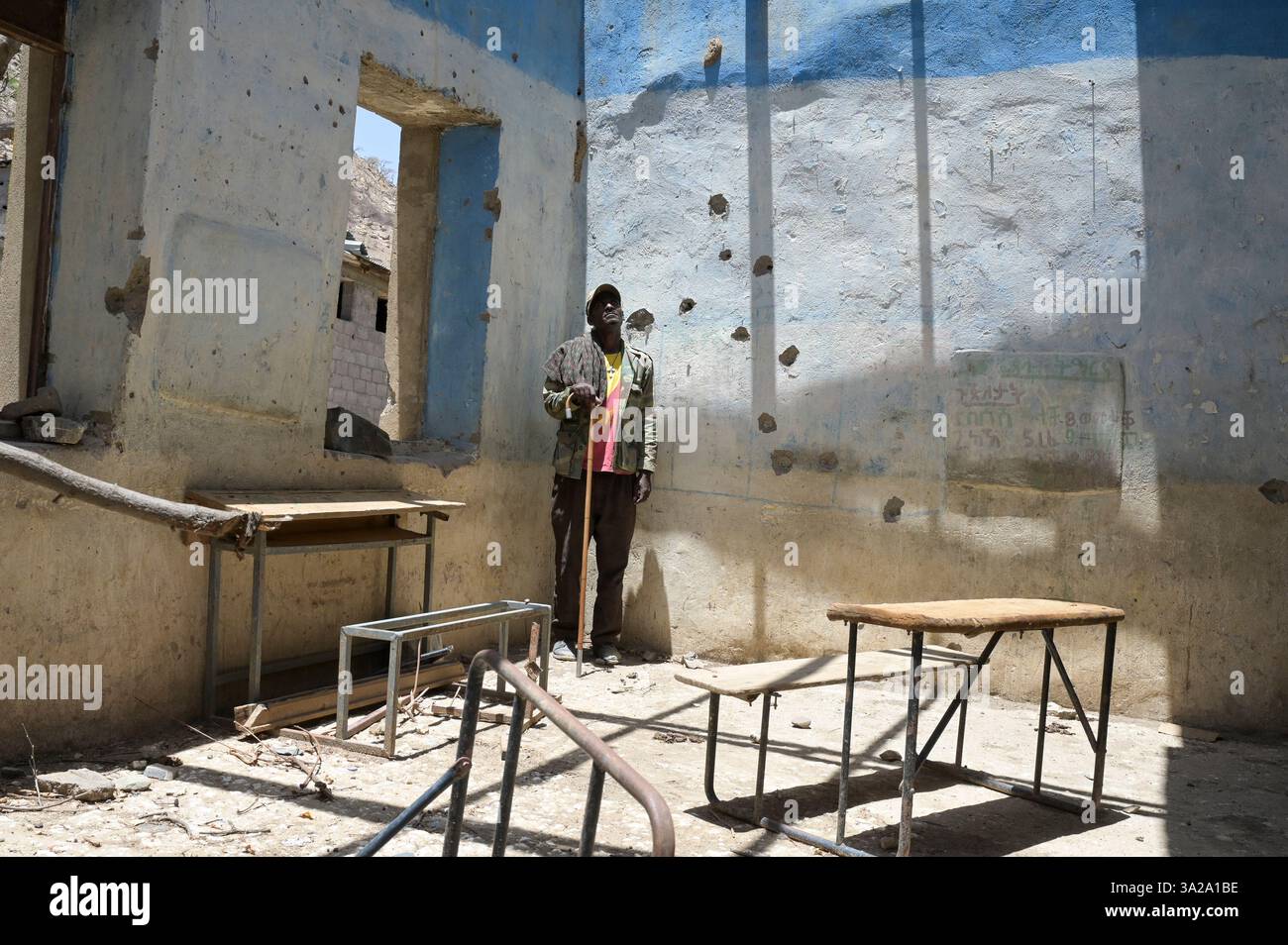 ETIOPIA, Distretto Yechila, villaggio SHEWEATE HUGUM, distrutto scuola durante la guerra Tigra 2020-2022 tra le forze alleate al governo federale etiope e l'Eritrea e il fronte di Liberazione del popolo Tigray TPLF, combattente TPLF / Äthiopien, Tigray, Folgen des Tigray Krieges 2020-2022, Distrikt Yechila, Dorf SHEWEATE HUGUM, zerstörte Schule, Gerse Tadese, Tigrayischer Kämpfer der TPLF, 51 Jahre alt, Sein Sohn ist im Krieg gefallen mit 22 Jahren, Gewehr Einschüsse Foto Stock