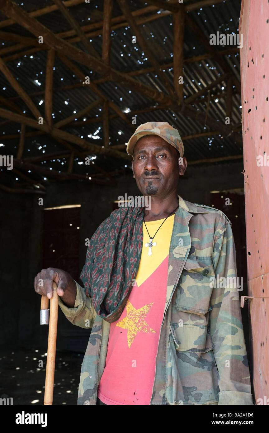 ETIOPIA, Distretto Yechila, villaggio SHEWEATE HUGUM, distrutto scuola durante la guerra Tigra 2020-2022 tra le forze alleate al governo federale etiope e l'Eritrea e il fronte di Liberazione del popolo Tigray TPLF, combattente TPLF / Äthiopien, Tigray, Folgen des Tigray Krieges 2020-2022, Distrikt Yechila, Dorf SHEWEATE HUGUM, zerstörte Schule, Gerse Tadese, Tigrayischer Kämpfer der TPLF, 51 Jahre alt, Sein Sohn ist im Krieg gefallen mit 22 Jahren, Gewehr Einschüsse Foto Stock