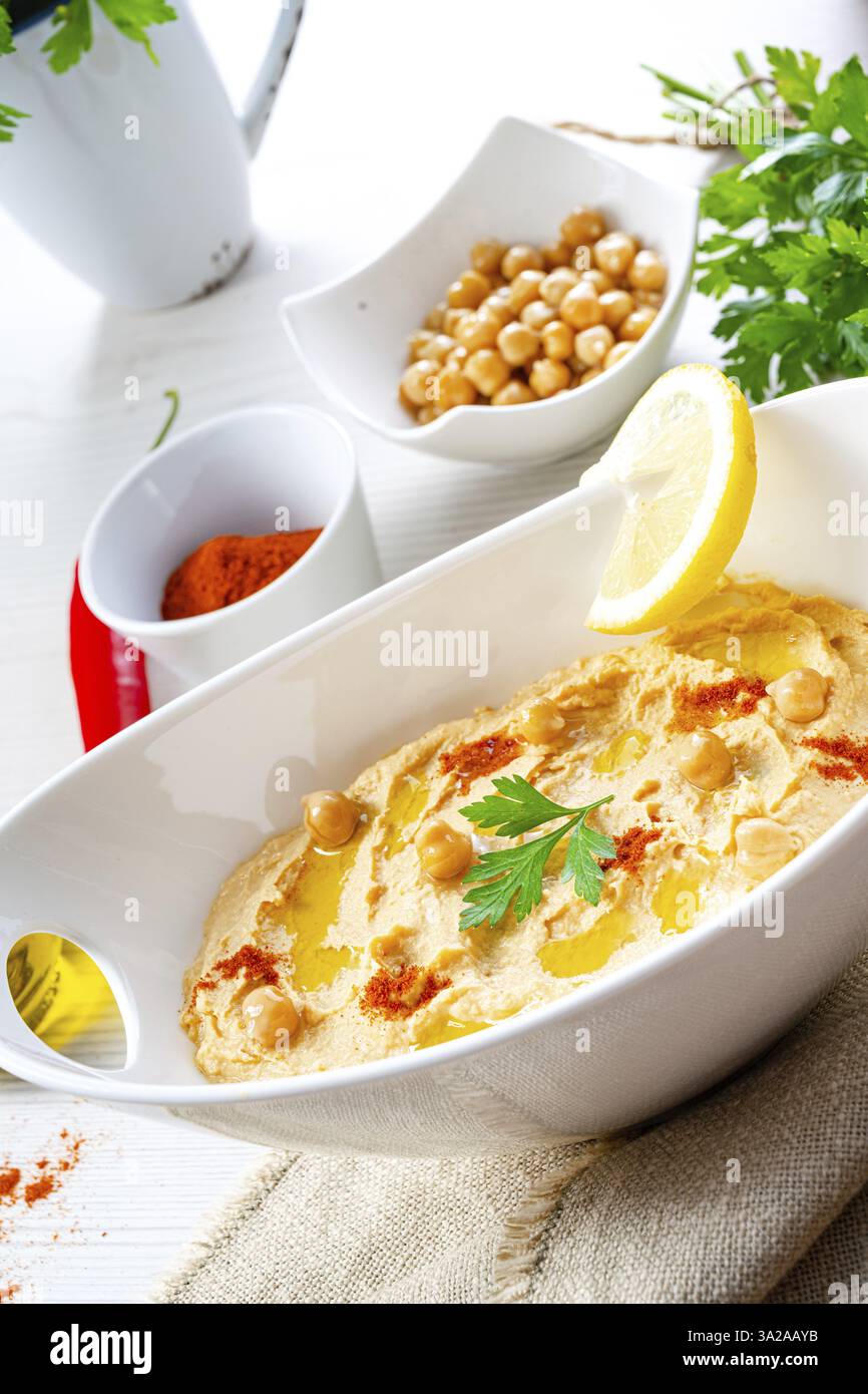 Pasta di hummus con limone e peperoncino su sfondo bianco Foto Stock