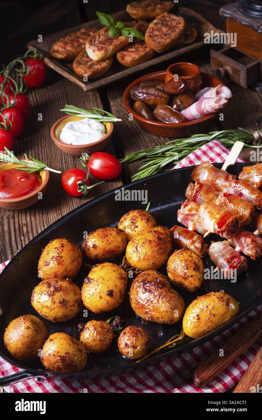 Datteri rustici avvolti in pancetta e patate arrosto giovani Foto Stock