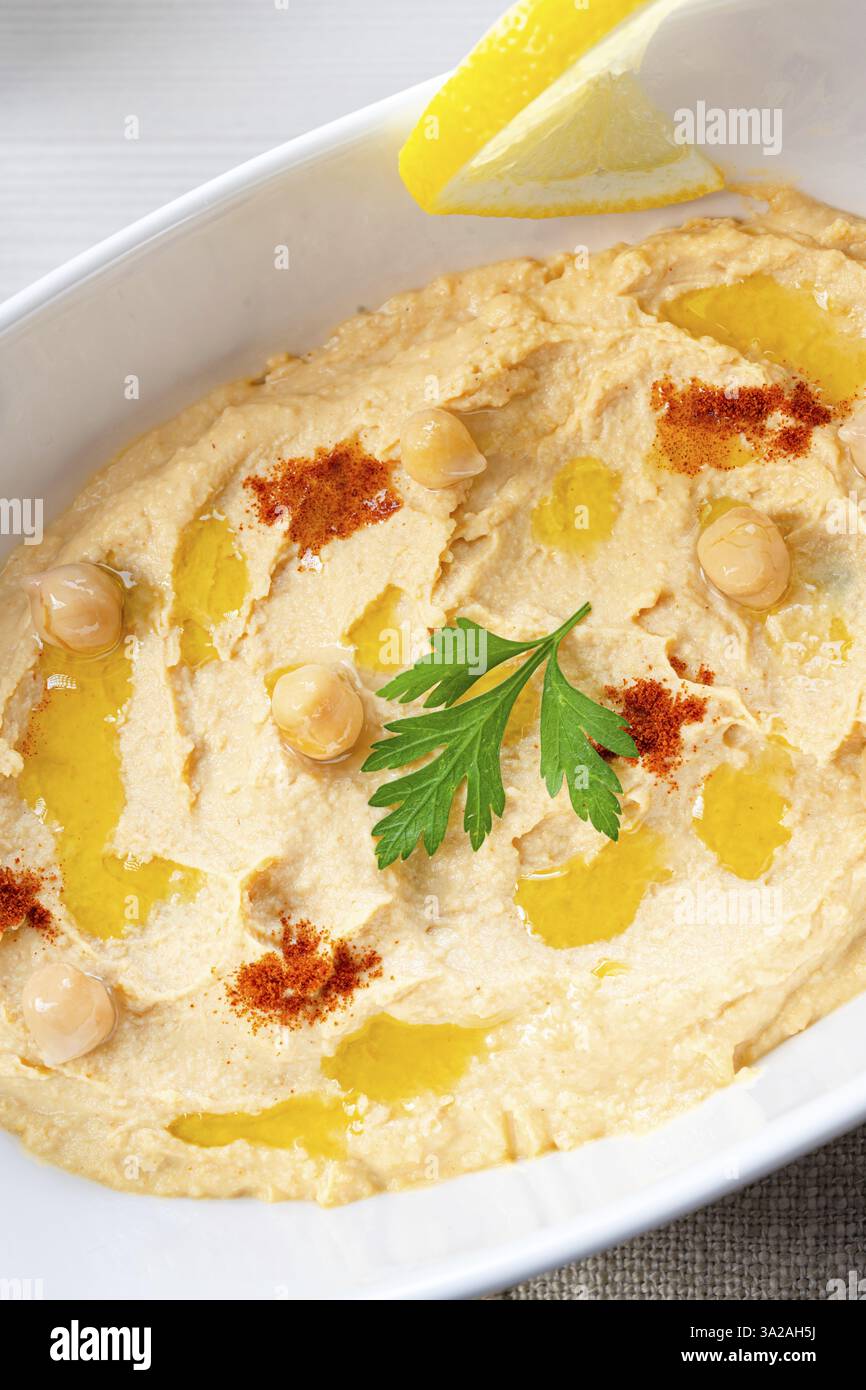 Pasta di hummus con limone e peperoncino su sfondo bianco Foto Stock
