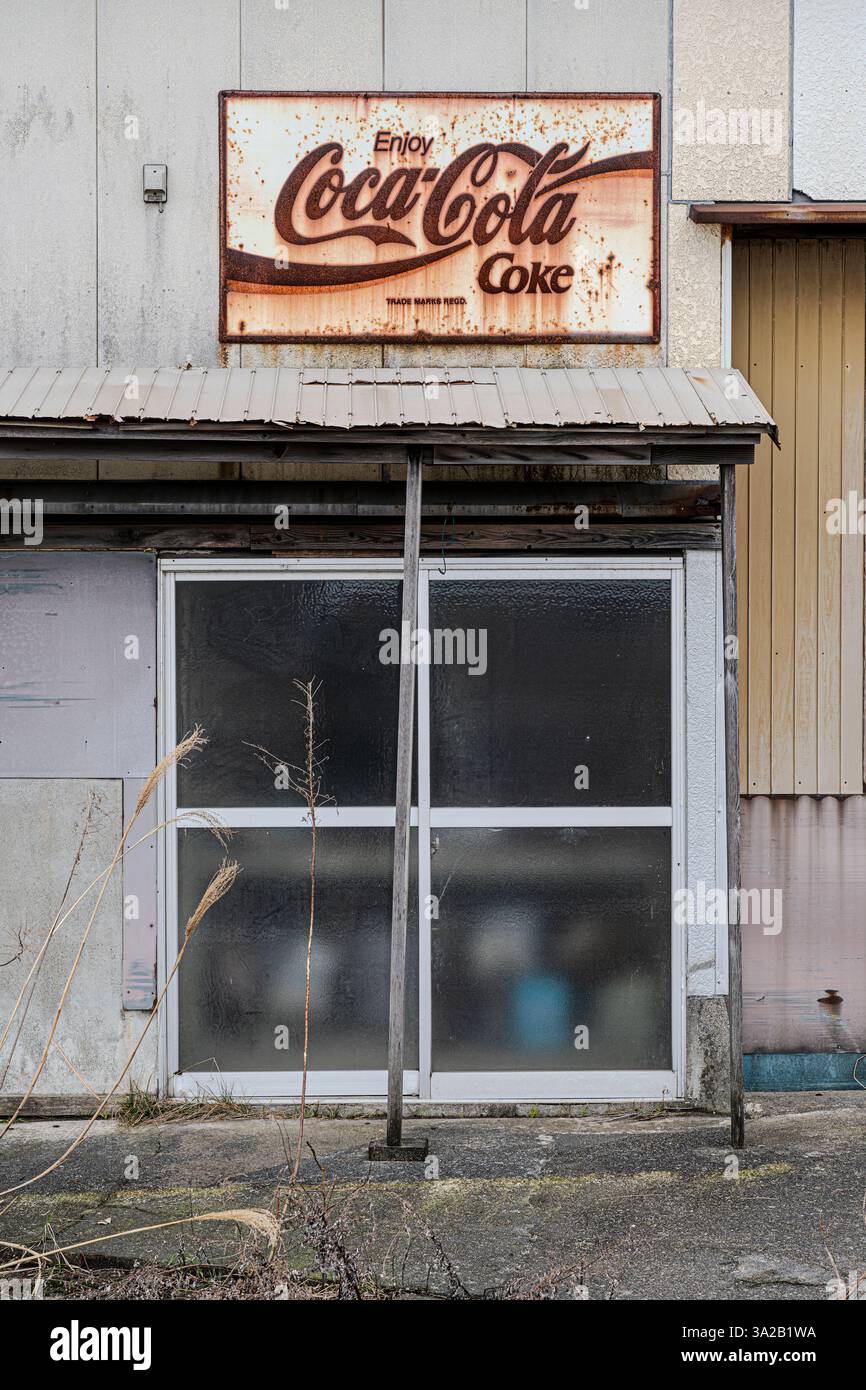 Un edificio decaduto con un cartello arrugginito della Coca Cola a Iwasehama, Toyama, Giappone. Foto Stock