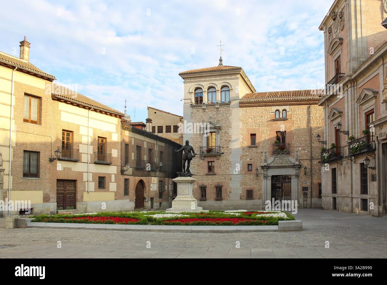 Una piazza storica di Madrid, Spagna, caratterizzata da una statua circondata da un'architettura antica. Foto Stock
