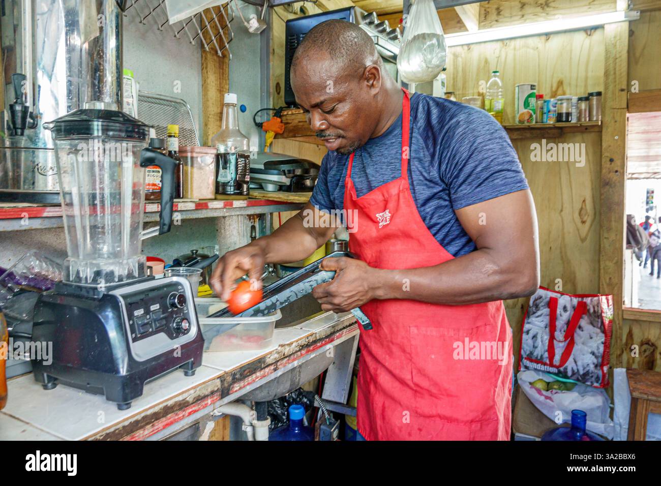 St. John's Antigua and Barbuda, vicino a Corn Alley, venditrice di cibo, uomo nero africano, lavoratore locale proprietario, preparatore di pasti e cena Foto Stock