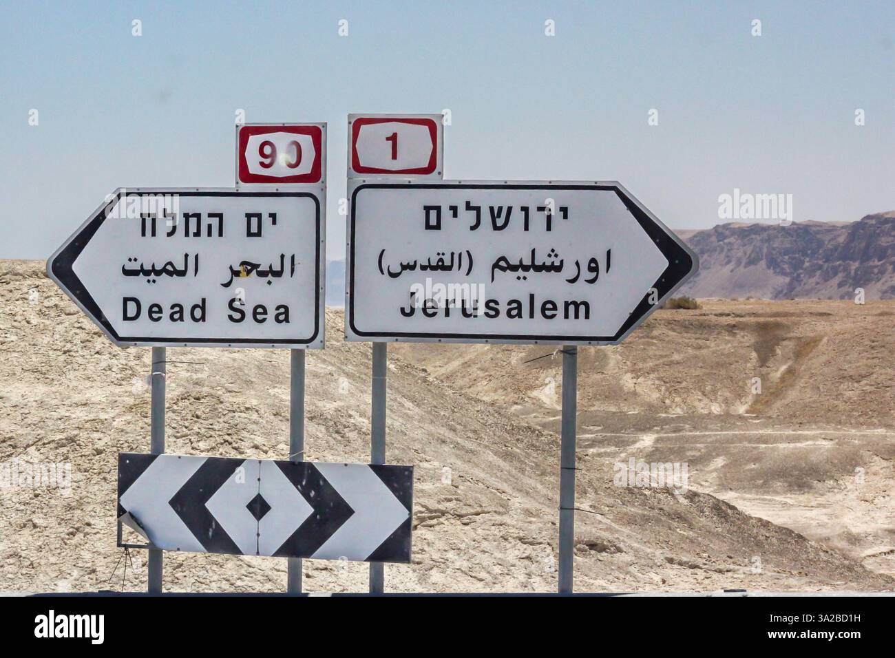I cartelli trilingue indirizzano i viaggiatori verso il Mar morto e Gerusalemme dall'intersezione delle autostrade 1 e 90 nel deserto Giudeo di Israele. Foto Stock