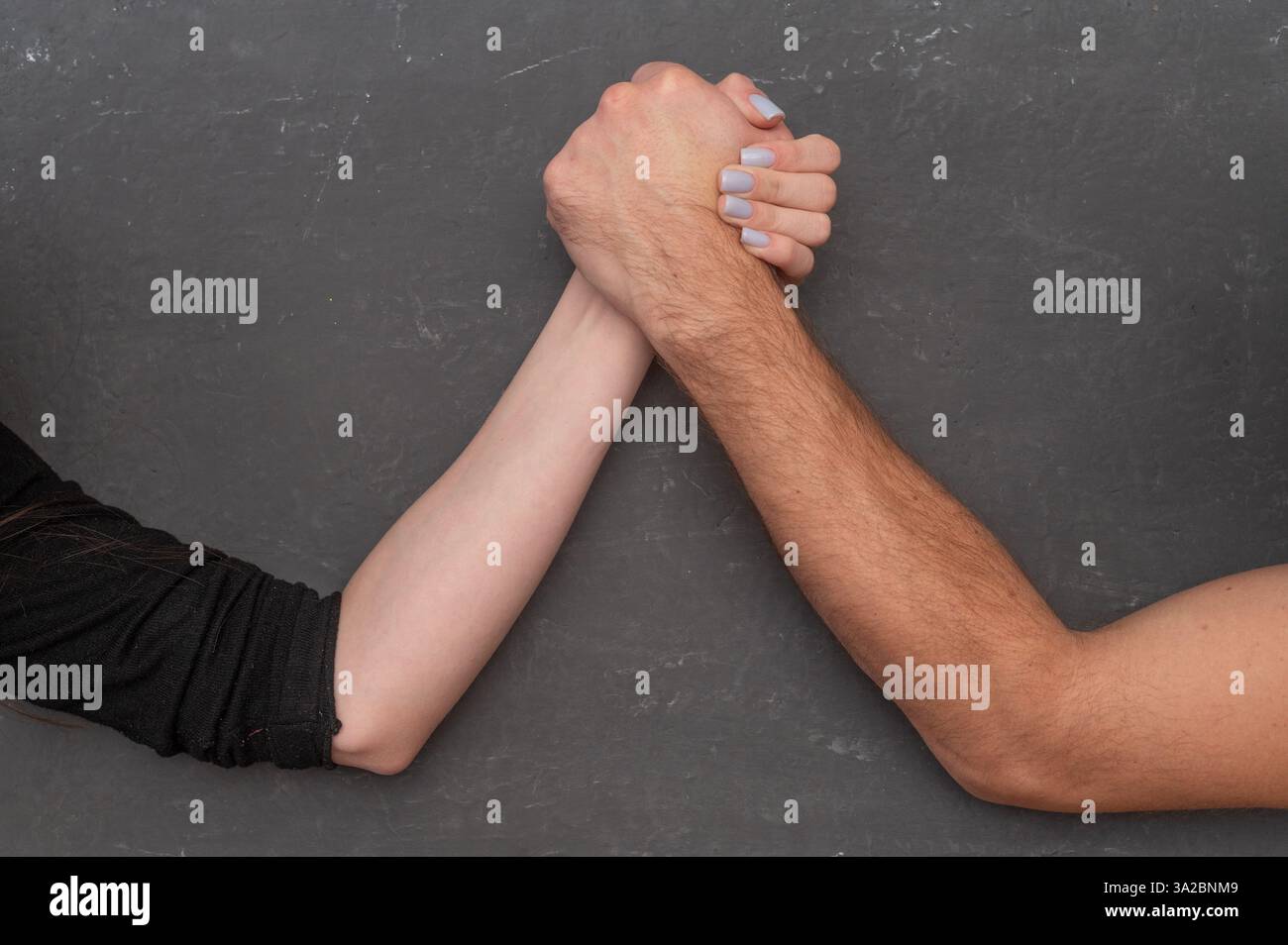 Un uomo e una donna competono nel braccio di ferro. Foto Stock