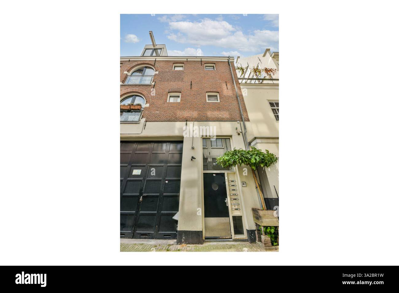 L'immagine mostra un'affascinante facciata in mattoni di un edificio storico caratterizzato da intricati dettagli architettonici e vegetazione in primo piano. Foto Stock