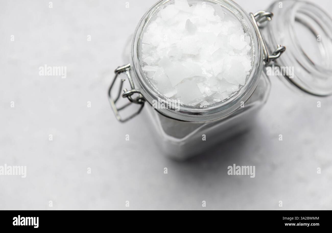 I fiocchi di cloruro di magnesio vengono conservati in un vaso di vetro con coperchio a chiusura metallica, favorendo rimedi naturali e rilassamento Foto Stock