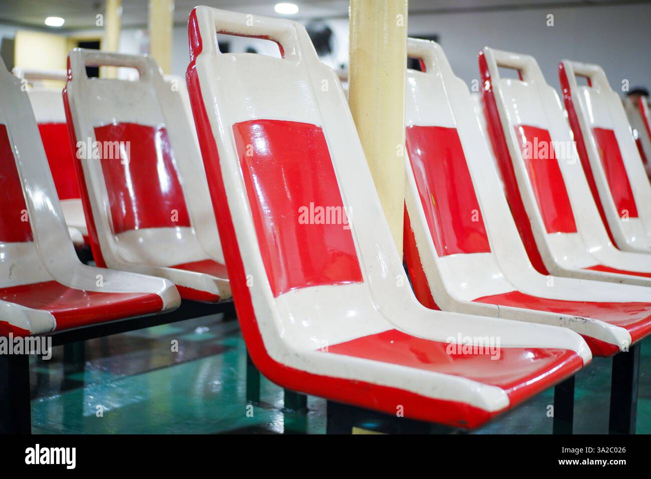 Posti passeggeri vuoti sul traghetto, sedie di plastica rosse e bianche nella camera di classe economica (traversata tra le isole, dal porto di Merak a Bakaheuni Har Foto Stock
