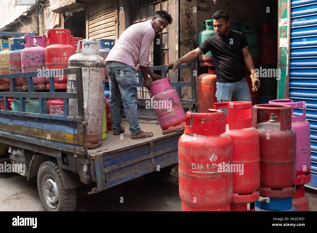 Uomini che scaricano un camion con bombole di gas, Dacca, Bangladesh Foto Stock