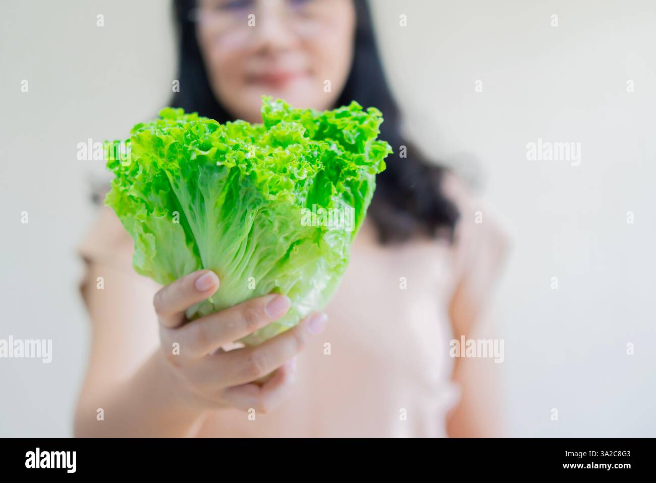 Lattuga romaina biologica che tiene per mano la donna, ingrediente alimentare per insalata sana. Messa a fuoco selettiva, copia spazio. Foto Stock