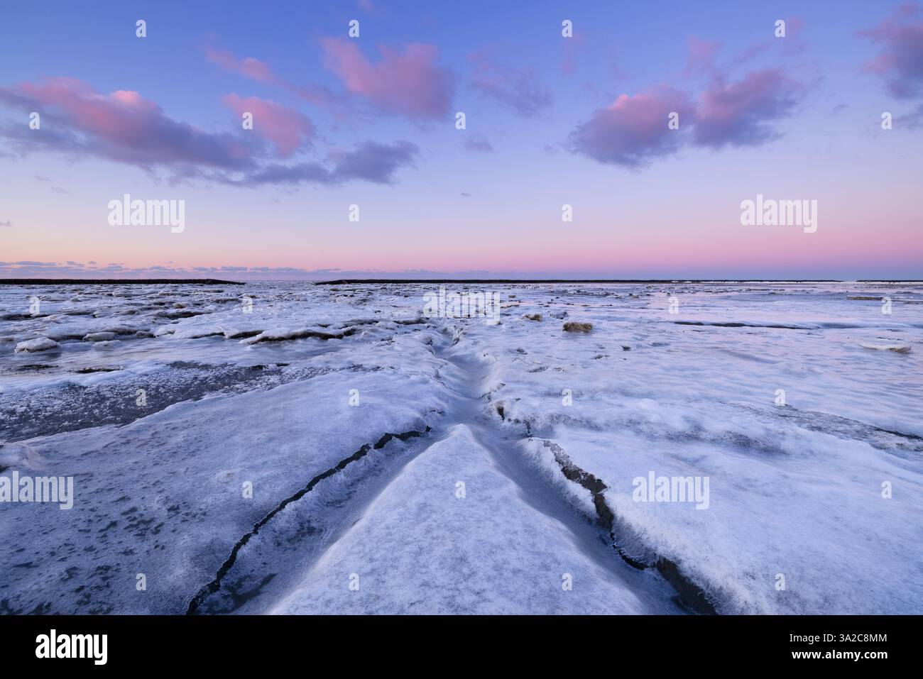 Un paesaggio invernale ghiacciato del Waddenzee nei Paesi Bassi con piattaforme ghiacciate e linee principali e un bel cielo - un freddo paesaggio invernale Foto Stock