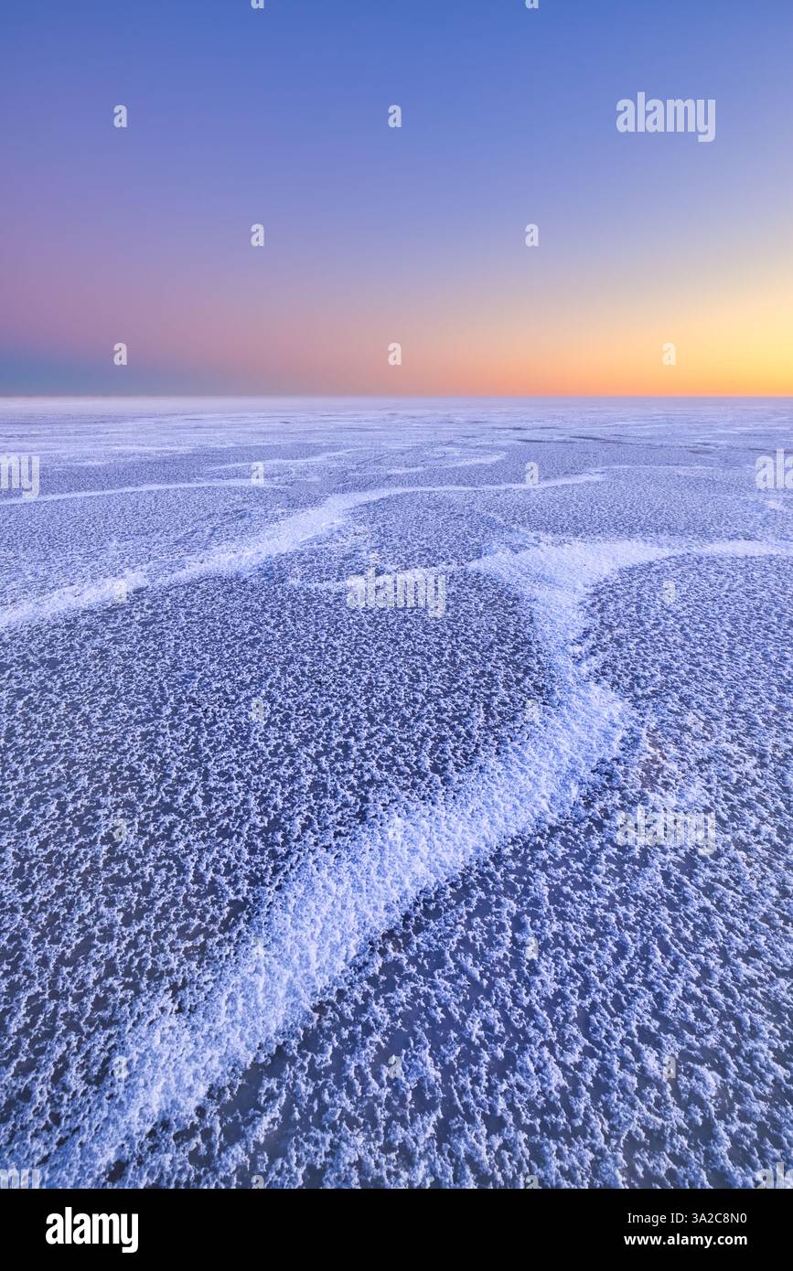 Un paesaggio polare con un lago ghiacciato e colori pastello del tramonto in inverno - un paesaggio invernale Foto Stock