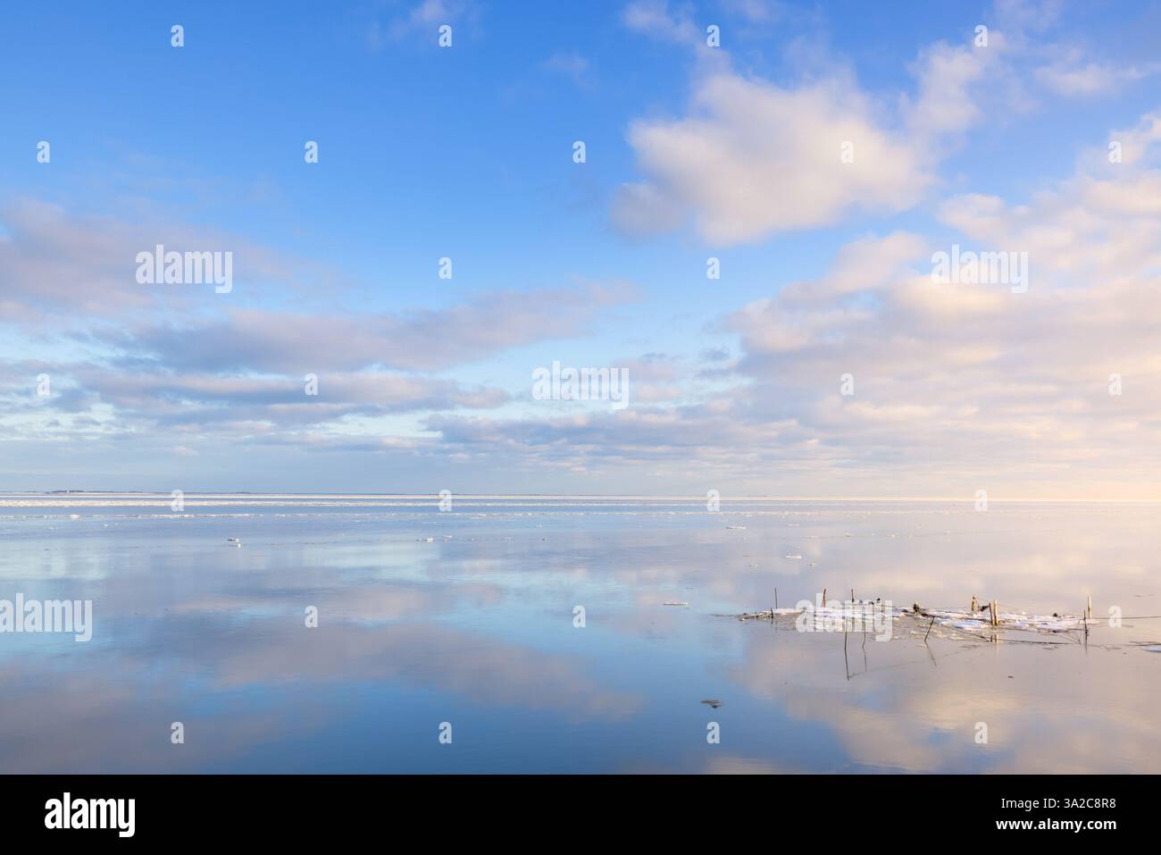 Un perfetto riflesso del Waddenzee in inverno a Groningen con nuvole nel cielo e piattaforma di ghiaccio sull'acqua come uno specchio Foto Stock Un perfetto riflesso del Waddenzee in inverno a Groningen con nuvole nel cielo e piattaforma di ghiaccio sull'acqua come uno specchio Foto Stock
