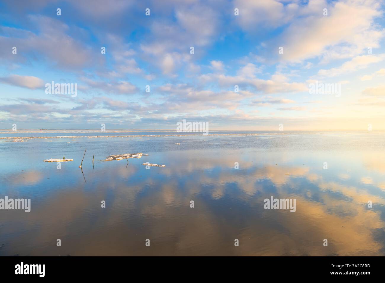 Un perfetto riflesso del Waddenzee in inverno a Groningen con nuvole nel cielo e piattaforma di ghiaccio sull'acqua come uno specchio Foto Stock Un perfetto riflesso del Waddenzee in inverno a Groningen con nuvole nel cielo e piattaforma di ghiaccio sull'acqua come uno specchio Foto Stock