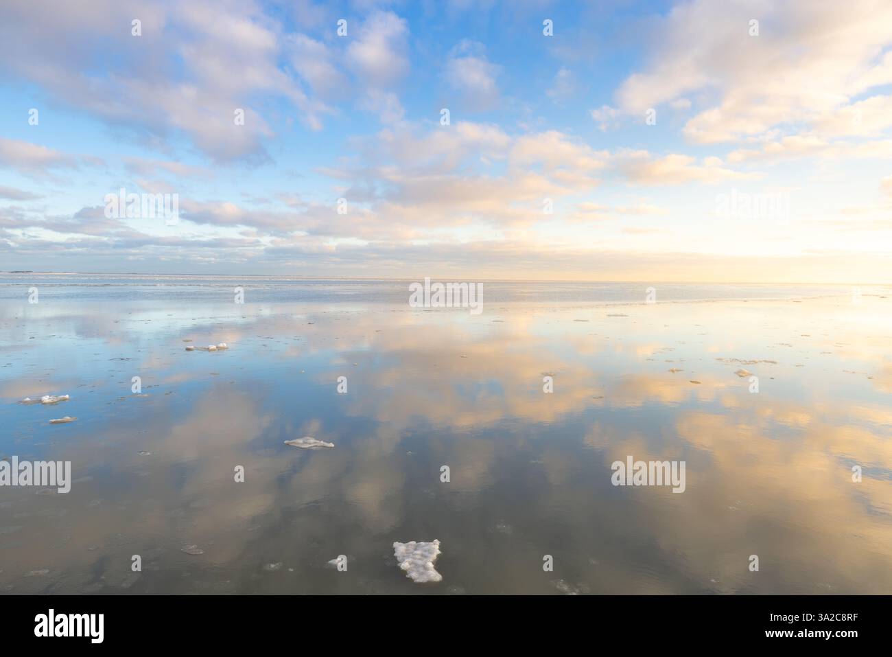 Un perfetto riflesso del Waddenzee in inverno a Groningen con nuvole nel cielo e piattaforma di ghiaccio sull'acqua come uno specchio Foto Stock Un perfetto riflesso del Waddenzee in inverno a Groningen con nuvole nel cielo e piattaforma di ghiaccio sull'acqua come uno specchio Foto Stock