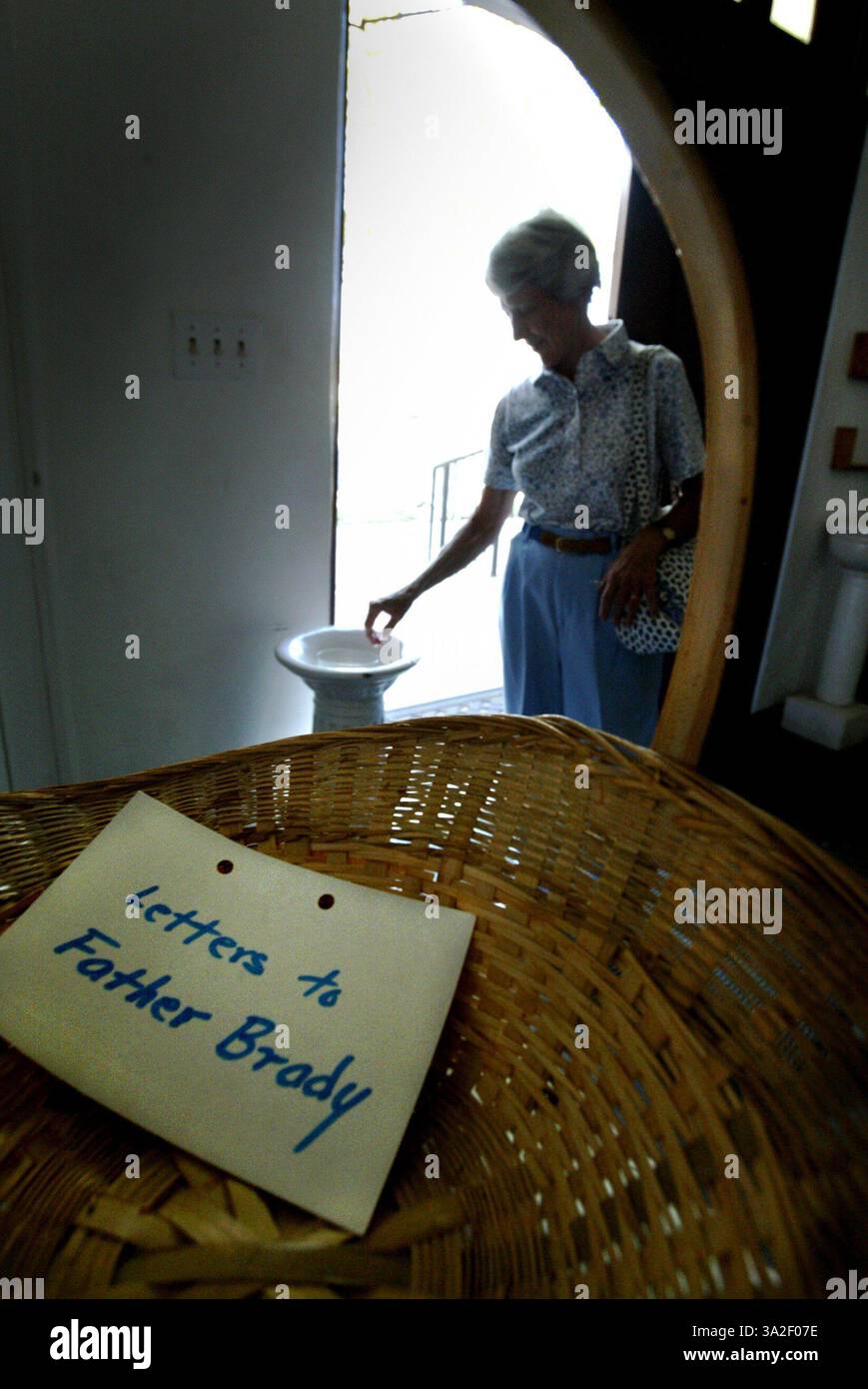 ALTERNATIVA LEDE SE NON C'è SPAZIO PER GESTIRE LA CONGREGAZIONE PREGANDO FOTO GRANDE, ABBINATA A QUESTA FOTO: Anna May Hobbs mette la mano nell'acqua Santa per fare il segno della croce mentre lascia la parrocchia di St. Josephs a Lincoln. In primo piano c'è un cestino per le lettere a padre Vincent Brady che è stato rimosso come pastore della loro chiesa. Foto scattata a Lincoln, giovedì 1 agosto 2002. (Credito: © Sacramento Bee/ZUMAPRESS.com) Foto Stock