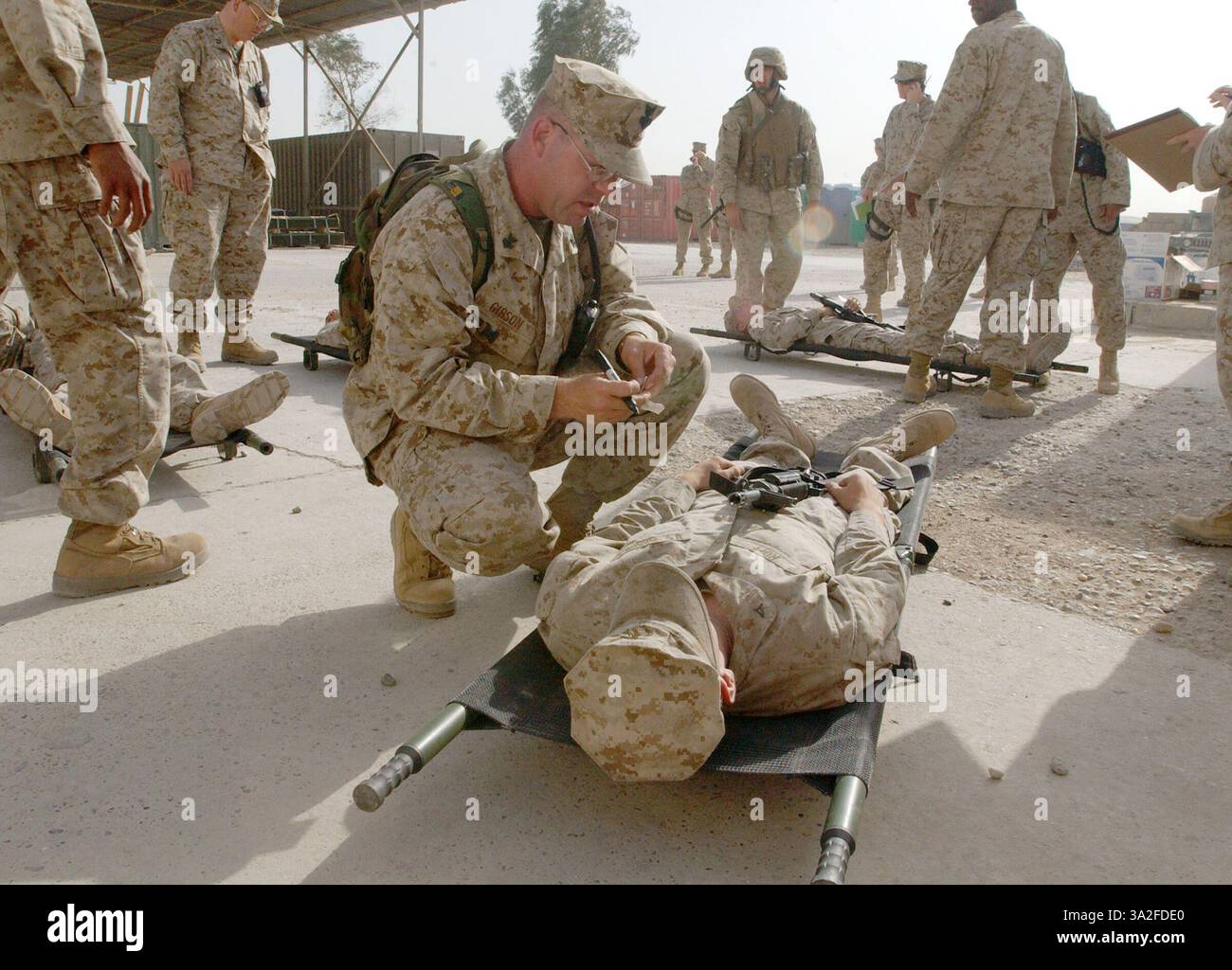 17 aprile 2004; Camp Mahmudiyah, Iraq; Navy Petty Officer 1st Class BARRY C. GIBSON, l'ufficiale di triage per il 2nd Battalion, 2nd Marine Regiment, 1st Marine Division si inginocchia sopra una vittima di ruolo dei Marine. Il corpsman dell'ospedale di Orottoes, Virginia, e i suoi colleghi medici hanno partecipato a un'esercitazione di massa per le vittime, dove i marines sono stati portati nella struttura medica del campo e curati per le ferite da combattimento. Il compito di Gibson è valutare immediatamente la gravità delle ferite del paziente e decidere quale livello di assistenza è necessario o se non può essere salvato. Foto Stock