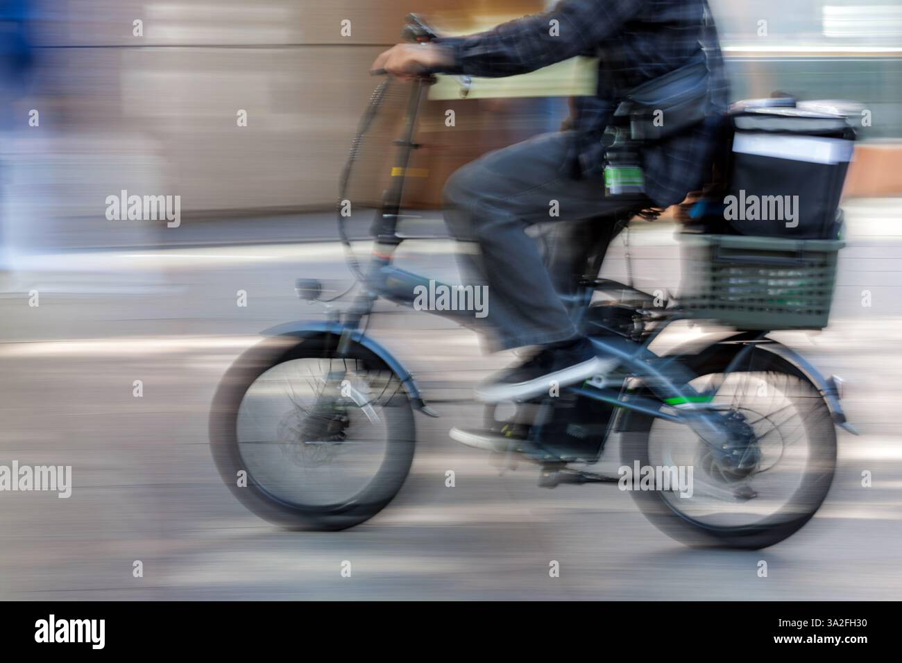 Motion Blur - il corriere di cibo giapponese attraversa la città di Nagoya su una piccola bicicletta motorizzata dotata di un grande cesto montato sul retro. Foto Stock