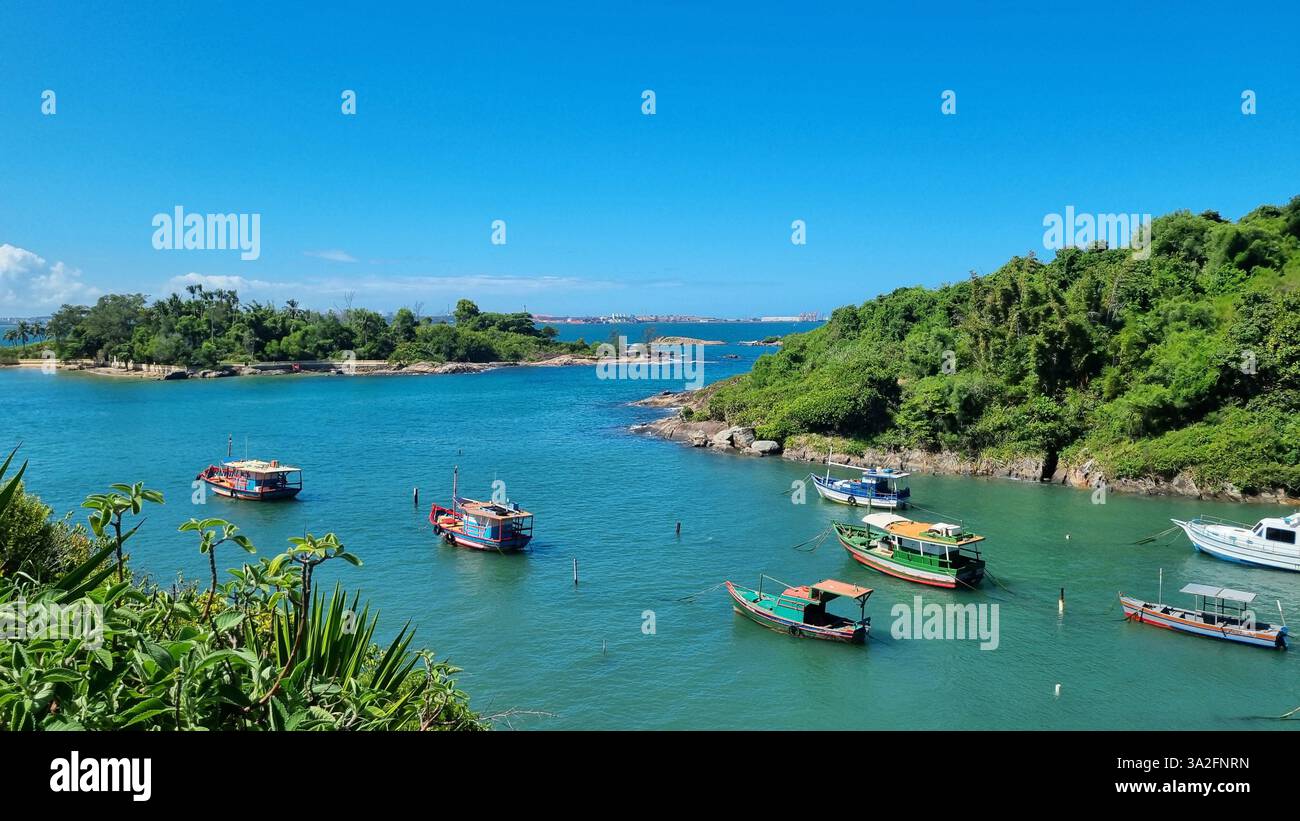 Una splendida scena costiera con vibranti acque turchesi, lussureggianti isole verdi e una serie di barche colorate che galleggiano dolcemente sul mare calmo. - Immagine stock catturata con smartphone