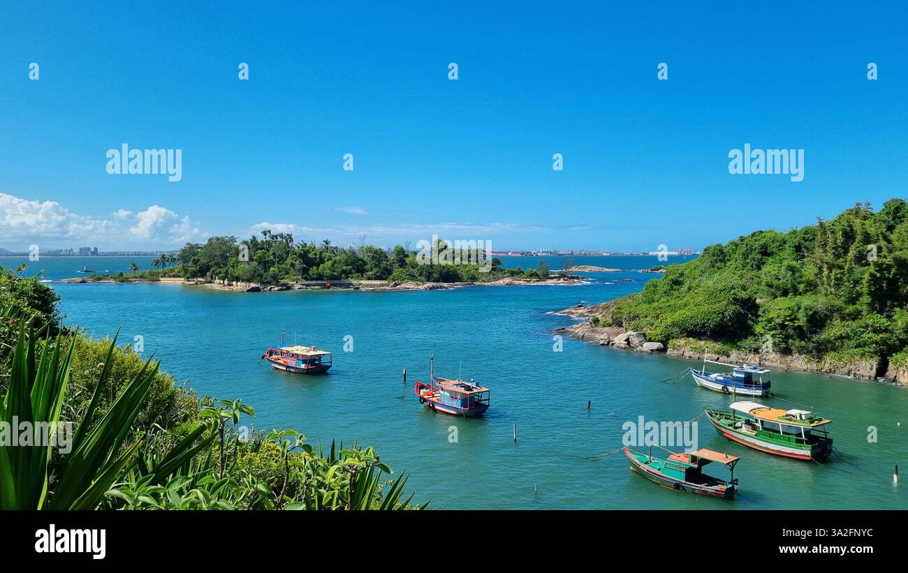 Una splendida scena costiera con vibranti acque turchesi, lussureggianti isole verdi e una serie di barche colorate che galleggiano dolcemente sul mare calmo. - Immagine stock catturata con smartphone
