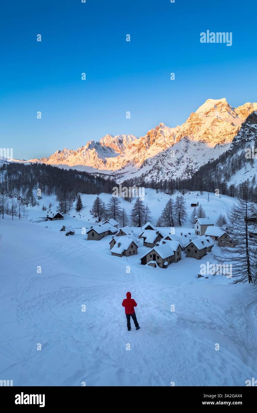 Una persona che ammira Crampiolo in inverno all'Alpe Devero. Alpe Devero, valle dell'Ossola, Piemonte, Verbano Cusio Ossola, Piemonte, Italia. Foto Stock