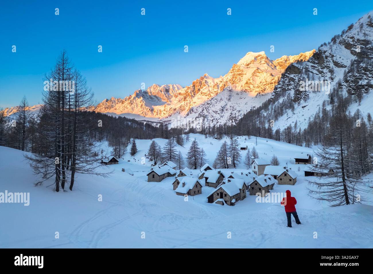 Una persona che ammira Crampiolo in inverno all'Alpe Devero. Alpe Devero, valle dell'Ossola, Piemonte, Verbano Cusio Ossola, Piemonte, Italia. Foto Stock