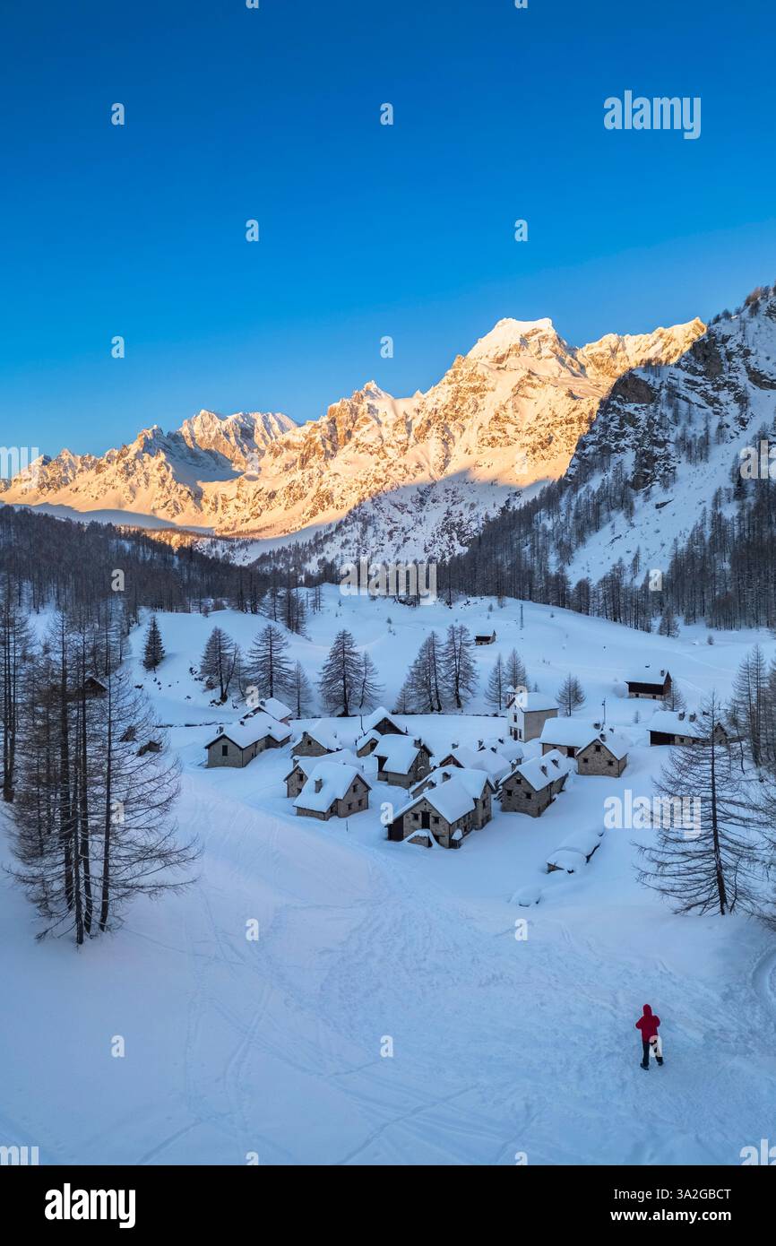 Una persona che ammira Crampiolo in inverno all'Alpe Devero. Alpe Devero, valle dell'Ossola, Piemonte, Verbano Cusio Ossola, Piemonte, Italia. Foto Stock