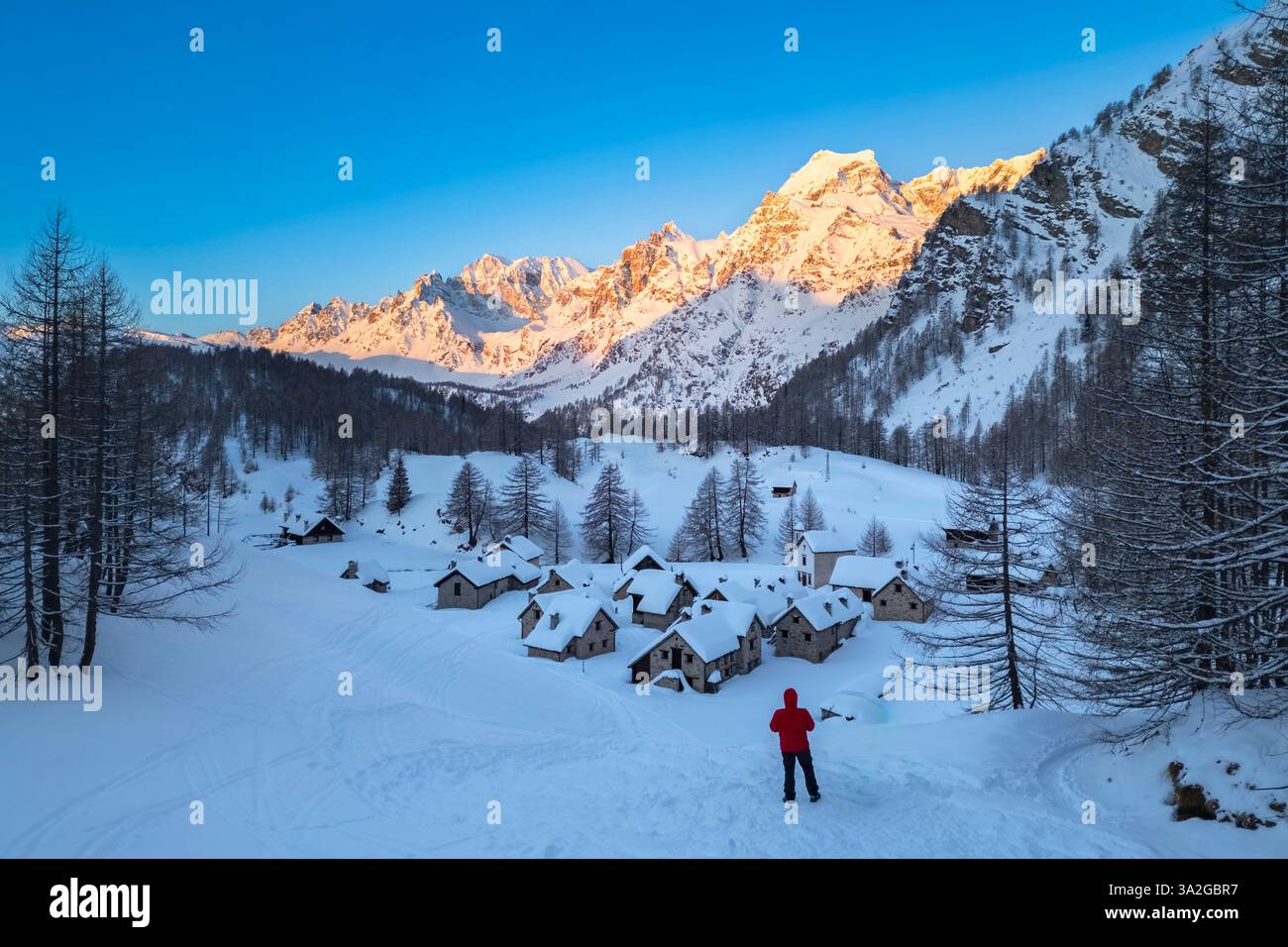 Una persona che ammira Crampiolo in inverno all'Alpe Devero. Alpe Devero, valle dell'Ossola, Piemonte, Verbano Cusio Ossola, Piemonte, Italia. Foto Stock
