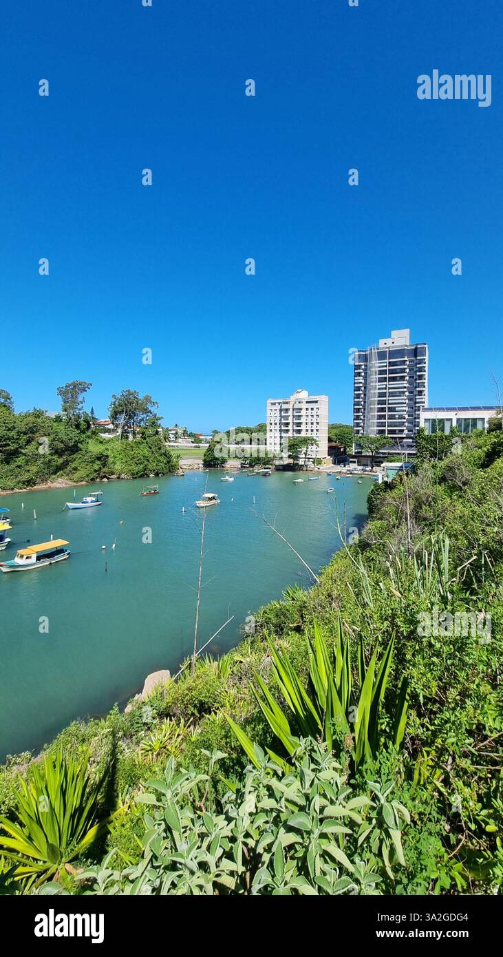 Una splendida scena costiera con vibranti acque turchesi, lussureggianti isole verdi e una serie di barche colorate che galleggiano dolcemente sul mare calmo - Immagine stock catturata con smartphone