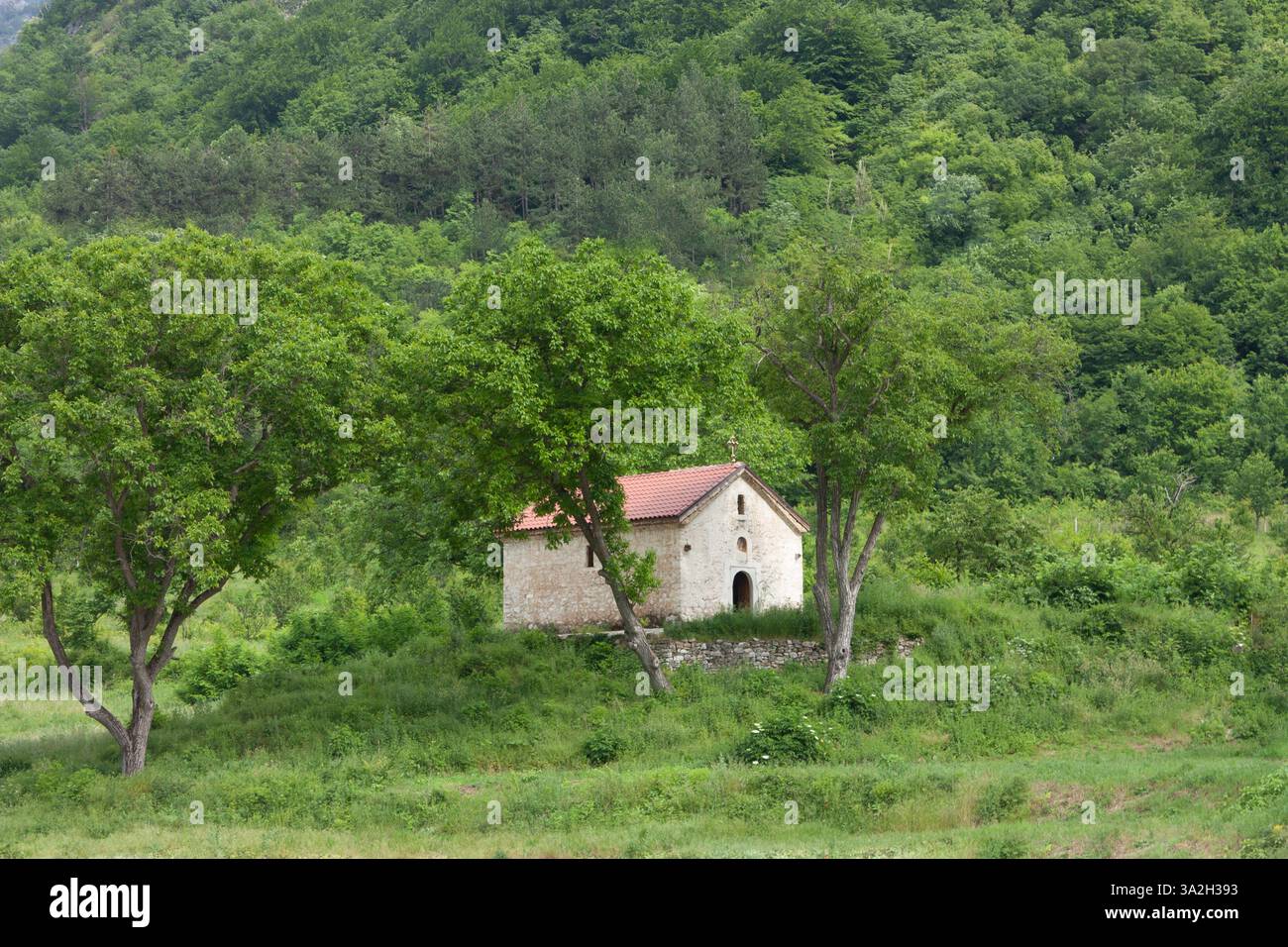 Una tranquilla cappella in pietra annidata nelle lussureggianti colline verdi vicino al Monastero di Bachkovo, Bulgaria, offre un rifugio tranquillo in un ambiente naturale mozzafiato Foto Stock