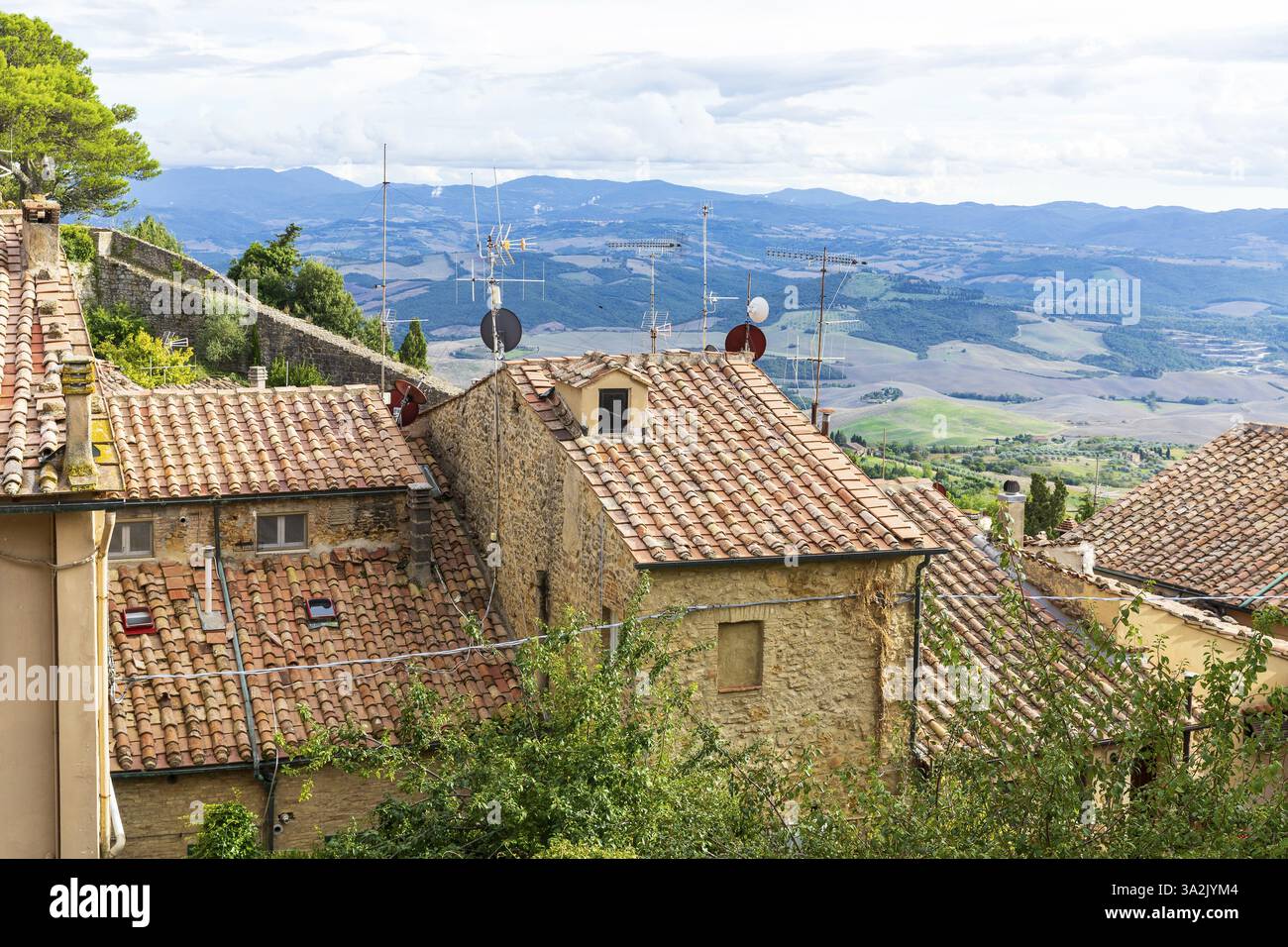 Molte antenne e antenne satellitari sui tetti antichi di Volterra, sullo sfondo delle colline della Toscana, della Provincia di Pisa, della Toscana, dell'Italia, dell'Europa Foto Stock
