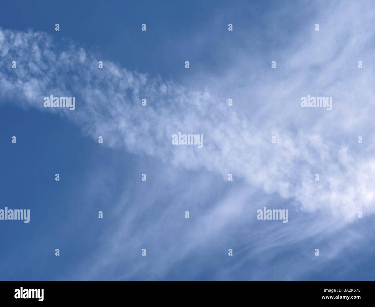 Dissolvendo la contrapposizione diagonale del jet Aircraft jet dietro nuvole bianche cirrostratus velo nuvole di fronte al cielo blu, internazionale Foto Stock