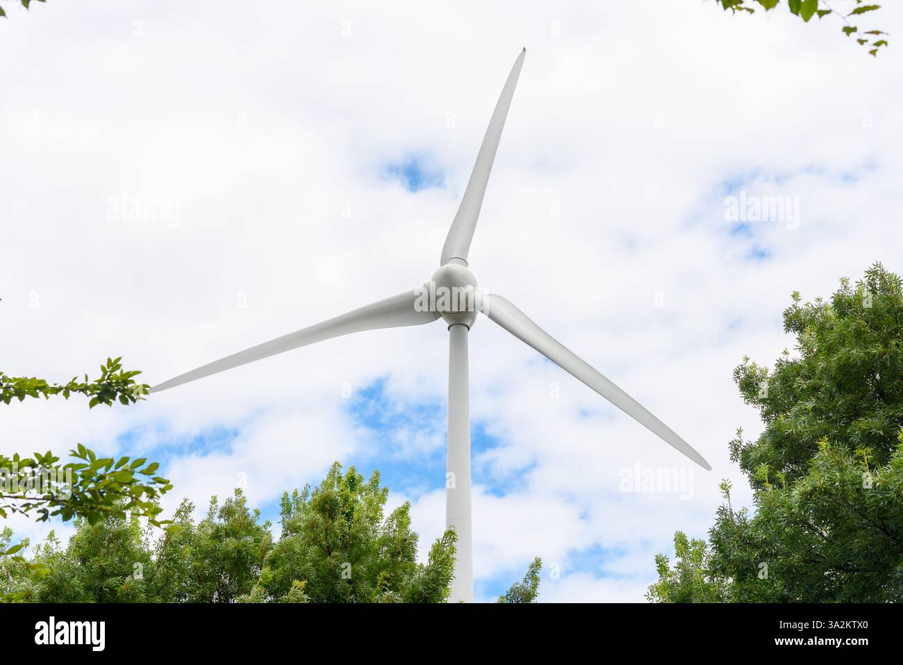 Dettaglio di una turbina eolica per la produzione di energia elettrica contro cielo parzialmente nuvoloso in estate Foto Stock