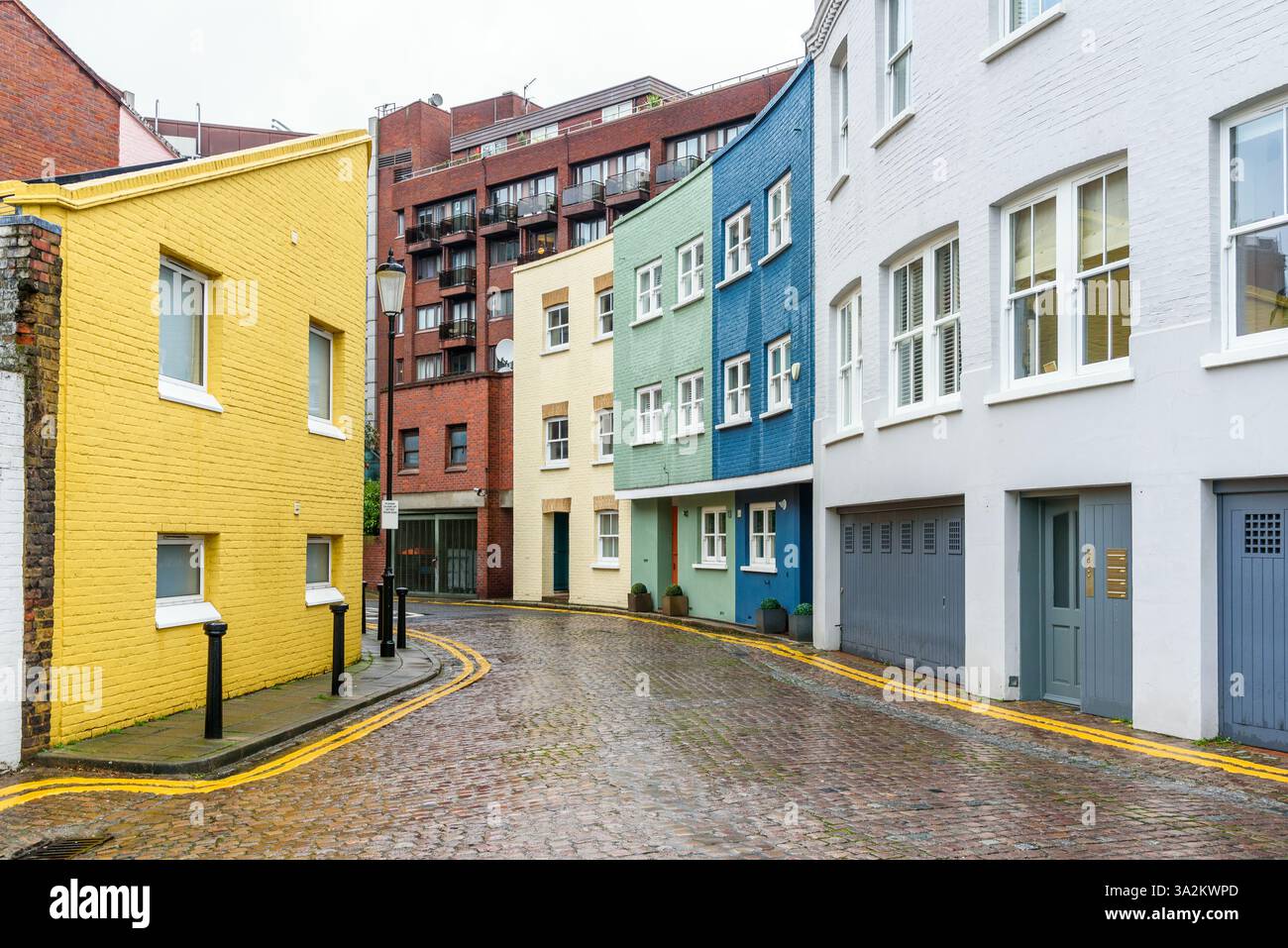 Case cittadine dai colori pastello lungo una stretta strada acciottolata a Londra in una giornata invernale piovosa Foto Stock