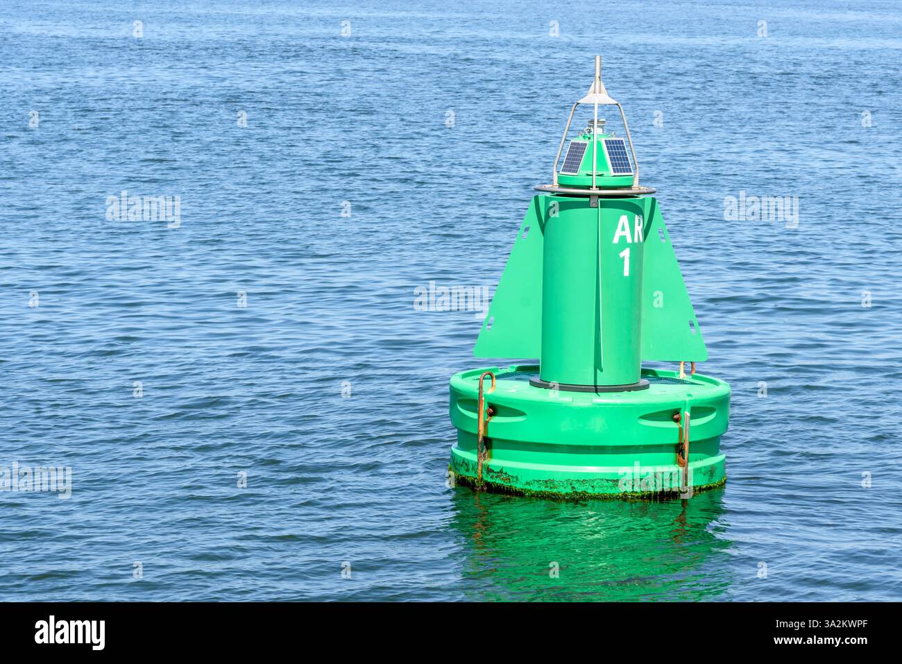 Primo piano della boa verde a energia solare che segna un canale di spedizione in un porto Foto Stock