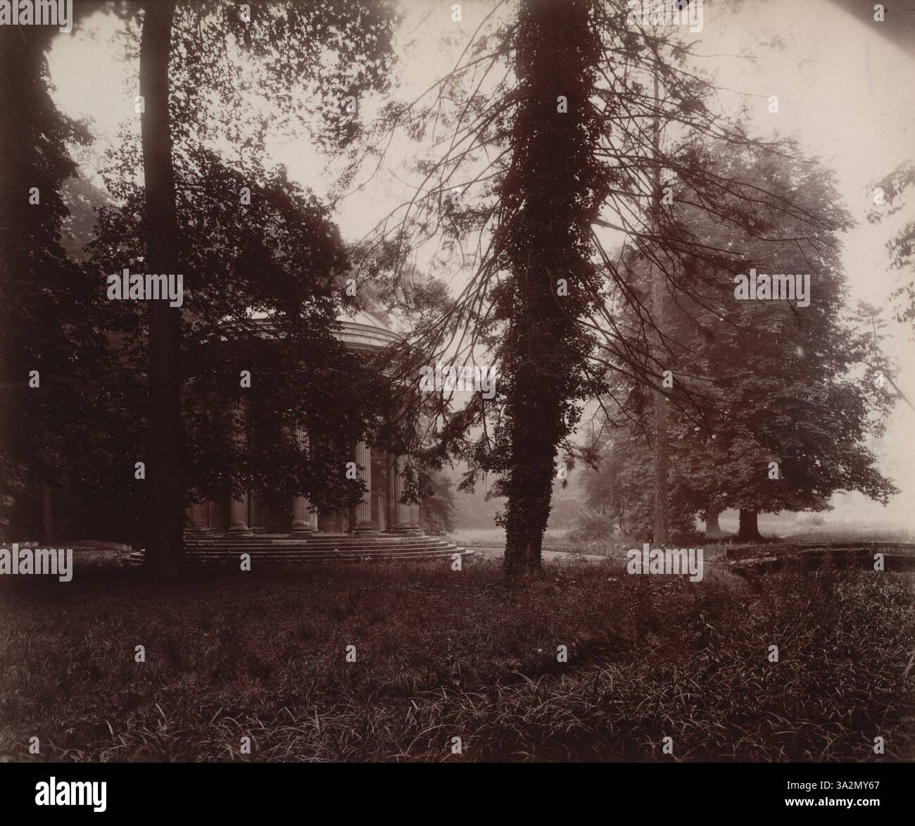 La fotografia di Eugène Atget del 1923-24 cattura il Tempio dell'amore al Grand Trianon di Versailles, visto attraverso gli alberi, offrendo uno scorcio dell'iconico monumento in un ambiente naturale. Foto Stock