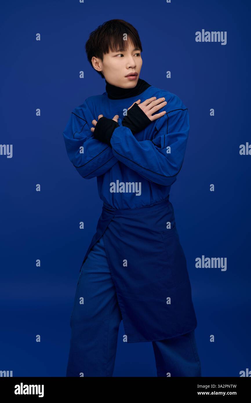 Un giovane e affascinante uomo asiatico con un elegante abbigliamento blu si posa con fiducia con un'espressione drammatica. Foto Stock Un giovane e affascinante uomo asiatico con un elegante abbigliamento blu si posa con fiducia con un'espressione drammatica. Foto Stock