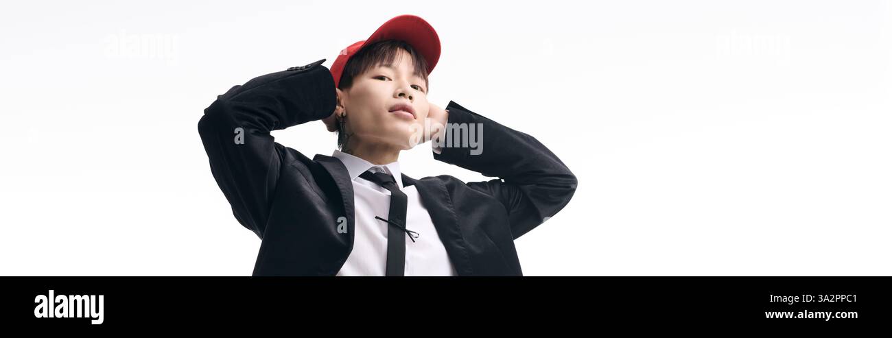 Il giovane e affascinante uomo asiatico ha una posa sicura, mescolando la moda moderna con un'atmosfera energica. Foto Stock