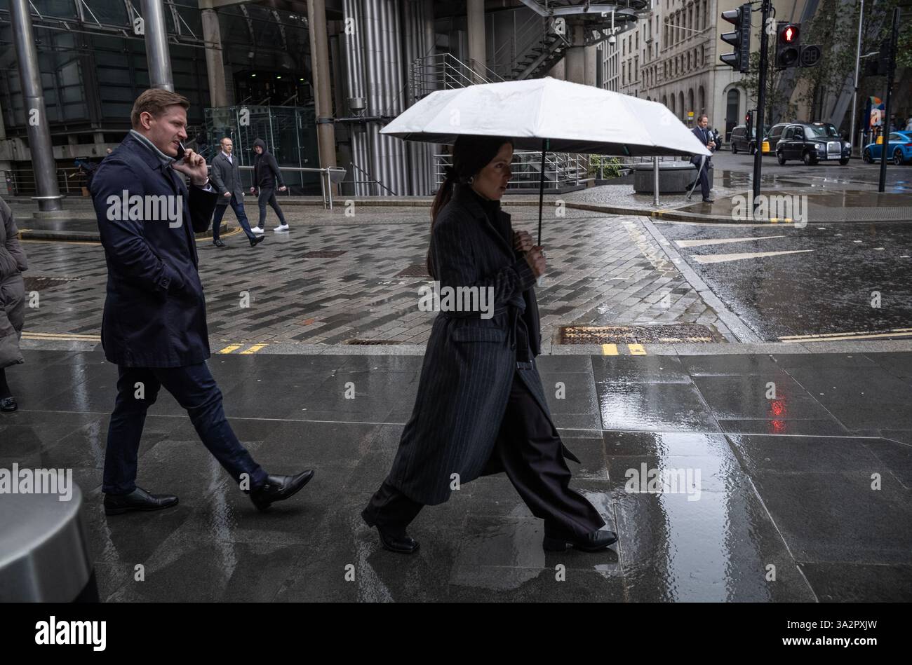 I lavoratori della città vengono catturati dalle forti piogge della primavera a Leadenhall Street, nel quartiere finanziario della City of London, Inghilterra, Regno Unito Foto Stock