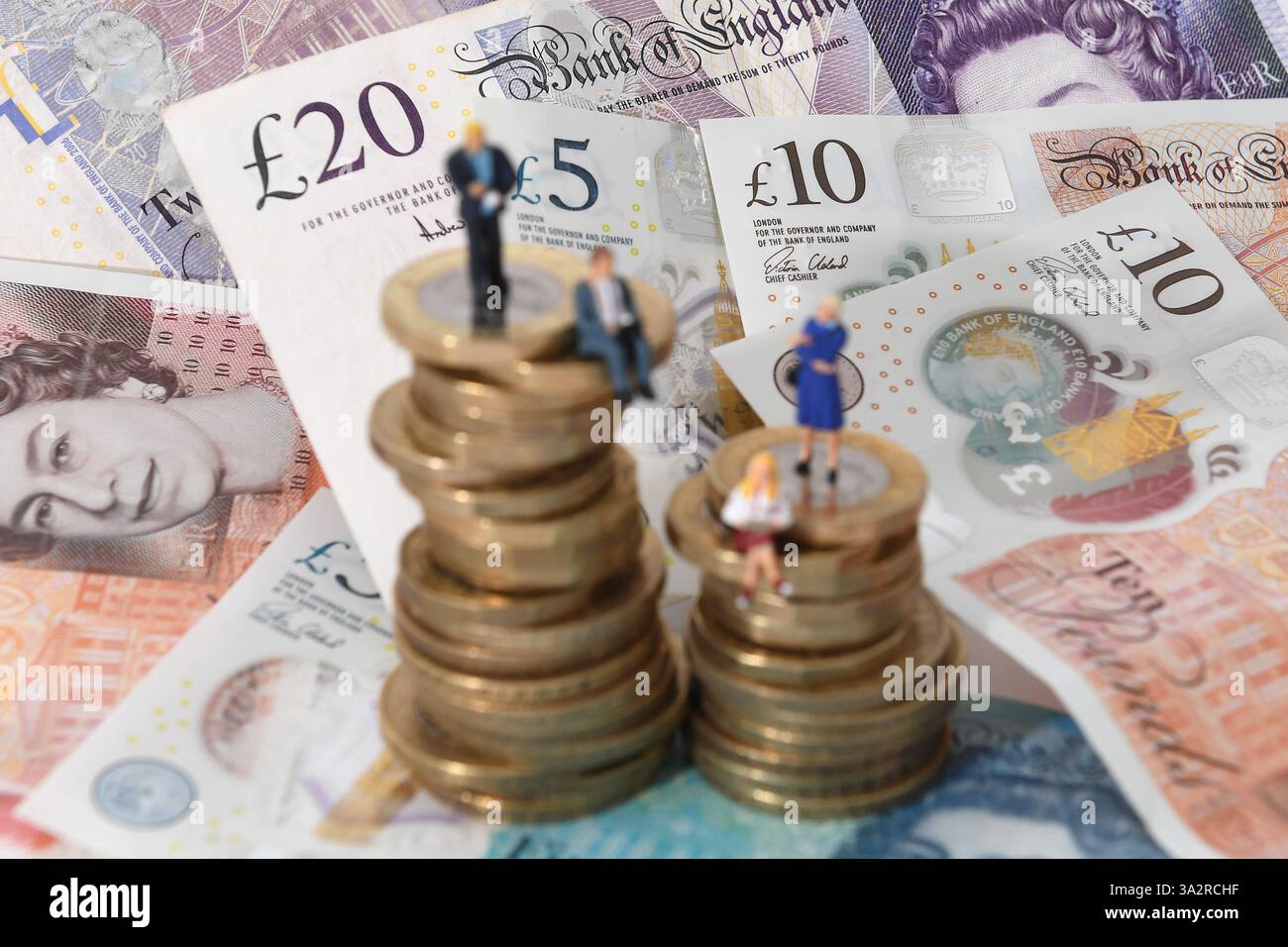 EMBARGO AL 0001 MERCOLEDÌ SETTEMBRE 25 file foto datata 12/09/18 di modelli di uomini e donne su una pila di monete e banconote. Le donne hanno maggiori probabilità degli uomini di tenere le uova di nido a lungo termine in un conto di risparmio invece di una Isa o pensione fiscale efficiente, come indica la ricerca. Quasi la metà (46%) delle donne detiene denaro destinato a lungo termine in un conto di risparmio, invece di una pensione o Isa, rispetto al 39% degli uomini, secondo Family Finance Tracker di Scottish Friendly. Data di pubblicazione: Mercoledì 25 settembre 2024. Foto Stock