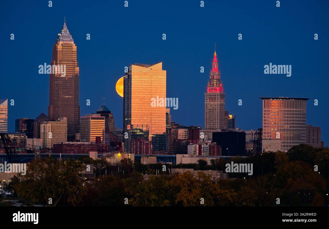 La luna piena che si innalza sopra Cleveland, Ohio, il 17 settembre 2024, sembra salire sul lato di uno dei grattacieli della città. Foto Stock