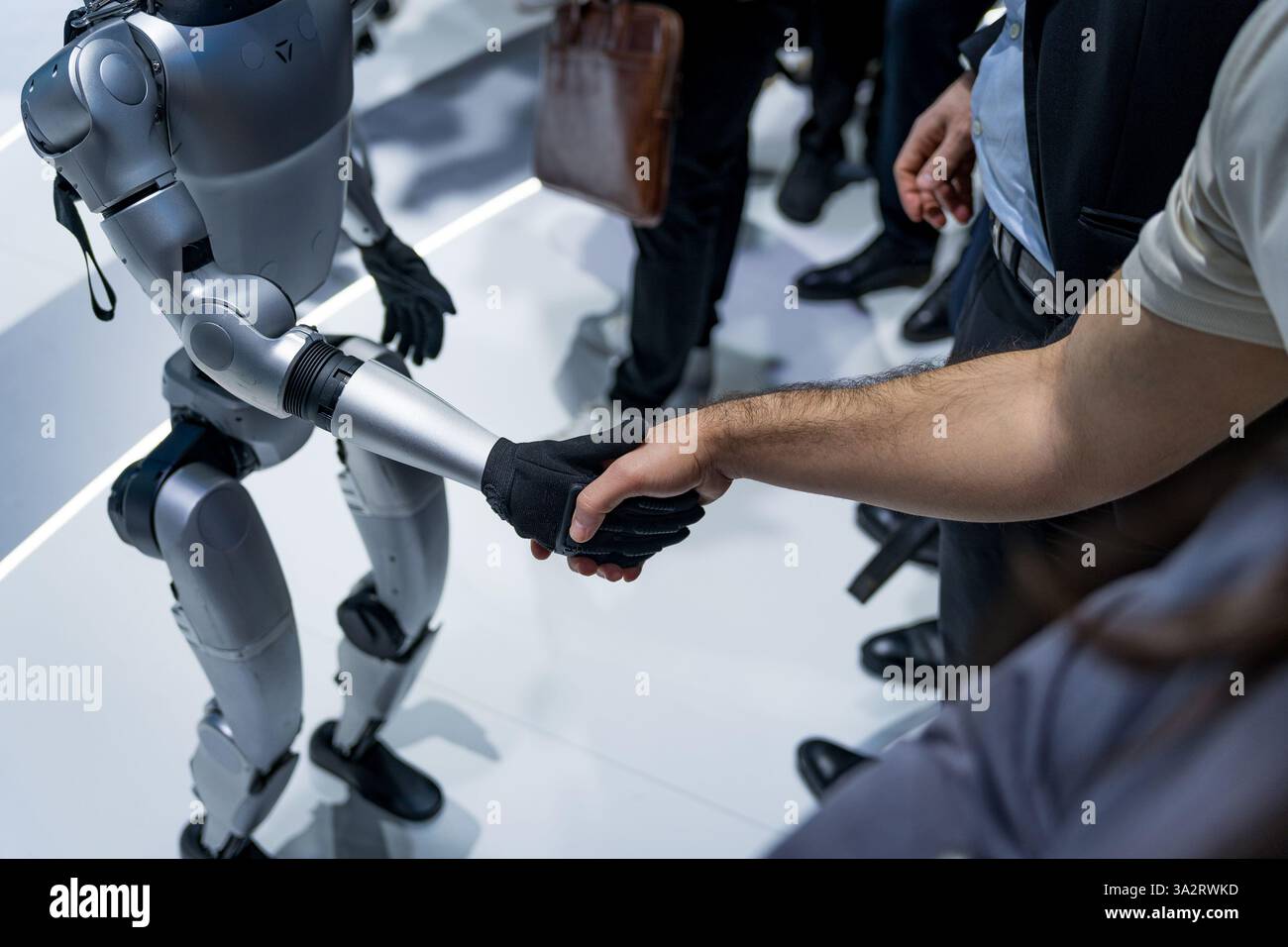 Un robot umanoide dell'azienda Unitree viene visto stringere la mano alle persone in una stretta di mano. Concetto di interazione umana e robotica e motore robotico Foto Stock