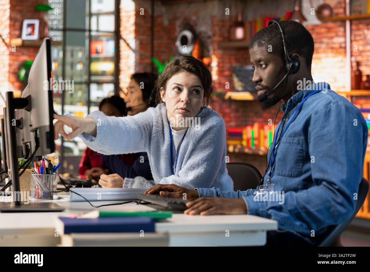 Addetto alla formazione di specialisti per l'acquisizione di call center su come utilizzare il software per computer. Supervisore nell'ufficio del reparto di assistenza clienti che mostra ai tirocinanti come utilizzare l'applicazione aziendale Foto Stock