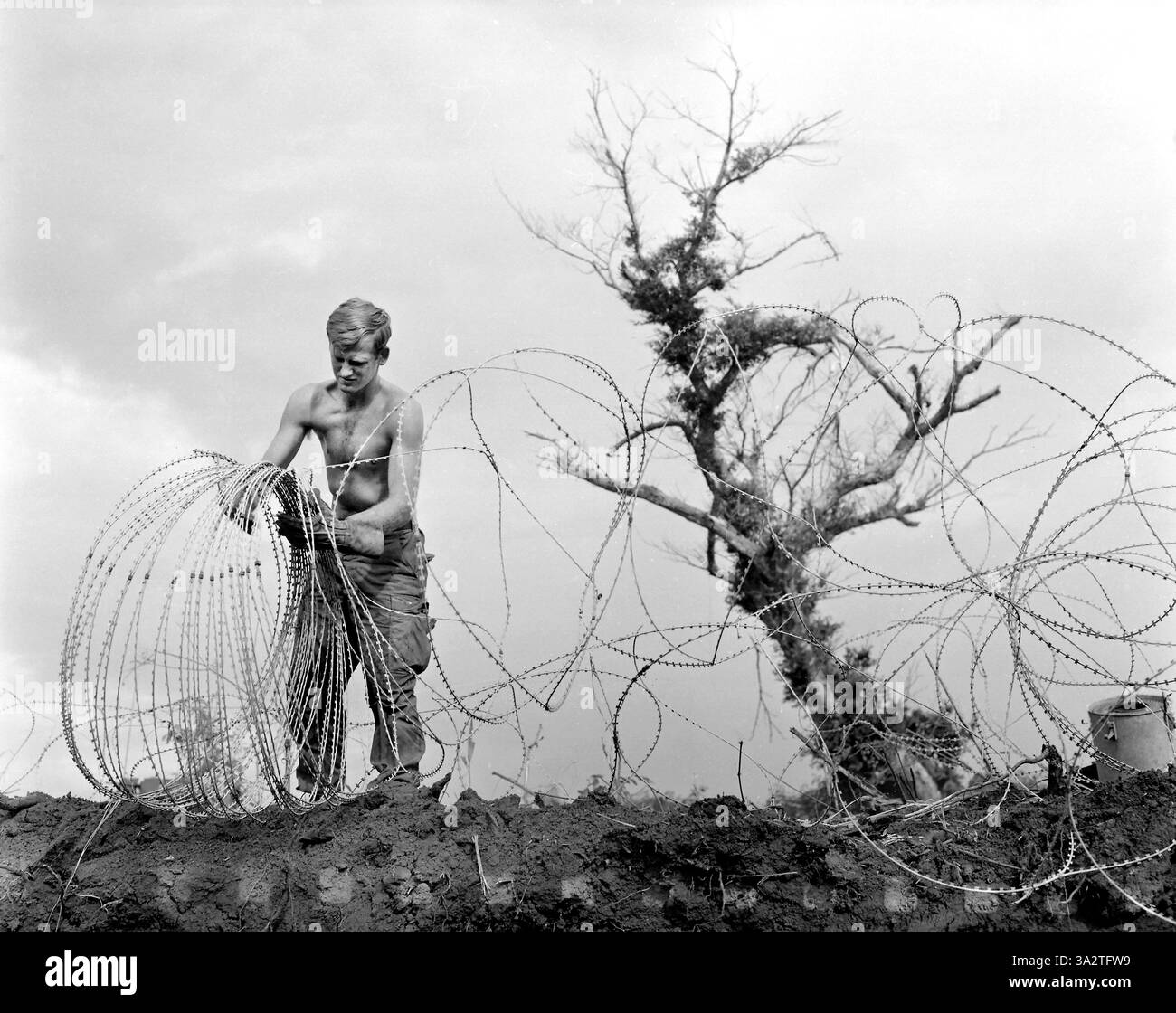 Membro della 1st Brigade, 5th Infantry Division (Mechanized), prendendo nastro spinato (forma modificata di filo di concertina) che circonda il posto di comando dell'operazione Utah Mesa, A Shau Valley, Vietnam, U.S. Army Signal Corps, luglio 1969 Foto Stock