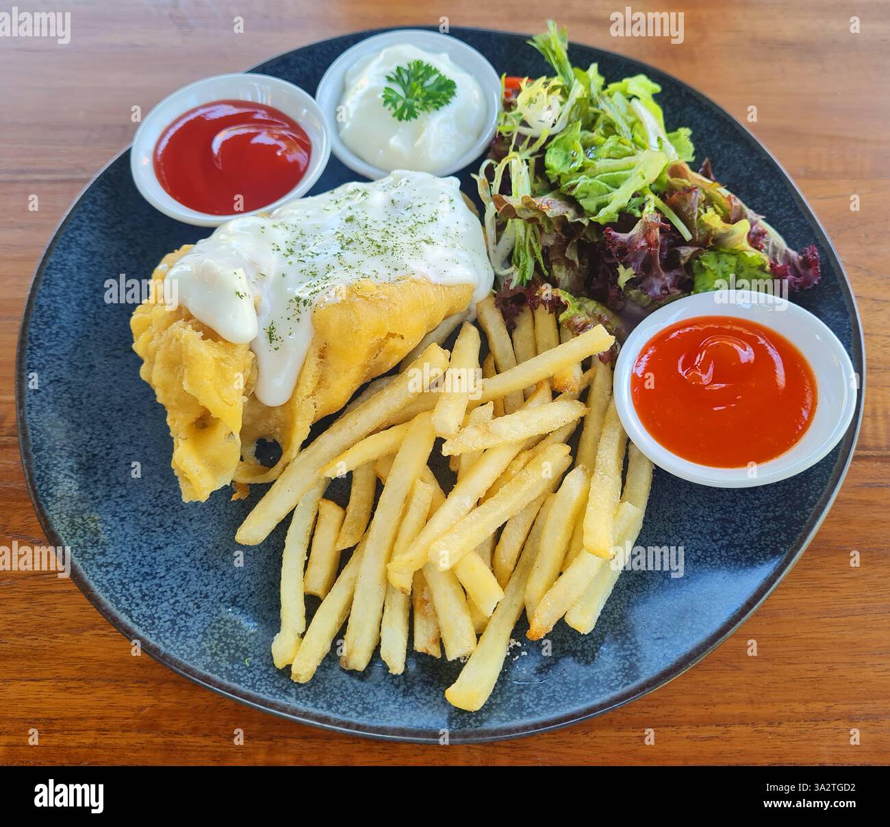 Pesce e patatine fritte con contorni di insalata e salsa di tartaro. Foto Stock