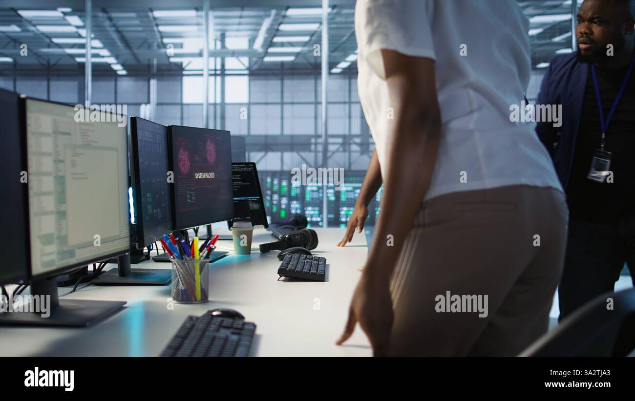 Gli ingegneri vedono un popup di violazione del sistema sullo schermo del PC nel data center, chiedendo aiuto al team di sicurezza informatica. Server farm worker che vede incidenti di sicurezza che interessano il sistema di rete, videocamera A. Foto Stock