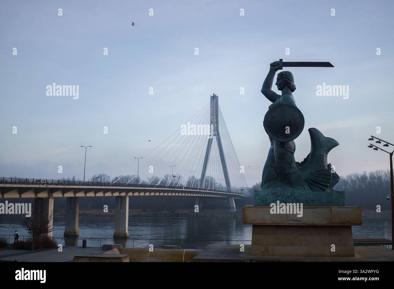 Varsavia, Polonia. 27 gennaio 2025 - Statua della Sirenetta con ponte Swietokrzyski sullo sfondo, mattina presto. Foto Stock