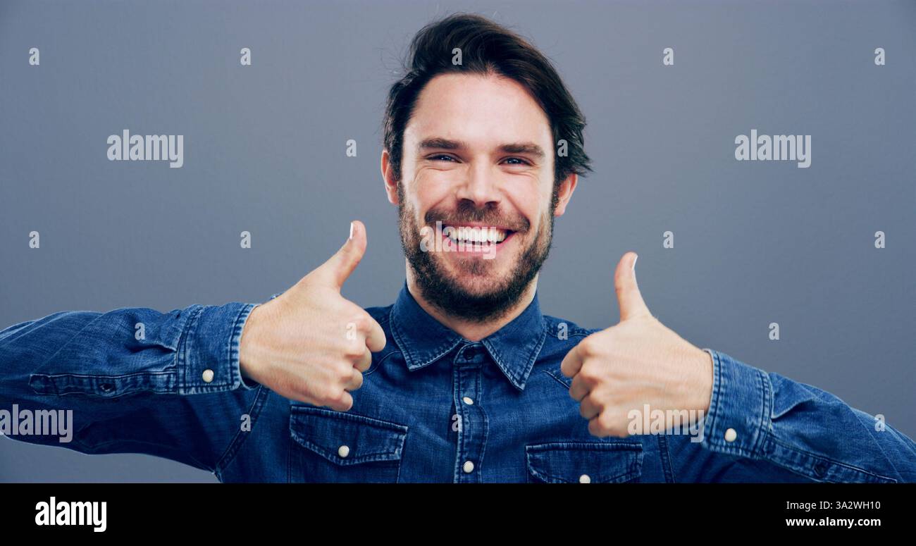 Pollice, sorriso e mani con ritratto dell'uomo in studio per approvazione, successo e feedback. Come emoji, sì firma e accordo con la persona maschile su Foto Stock